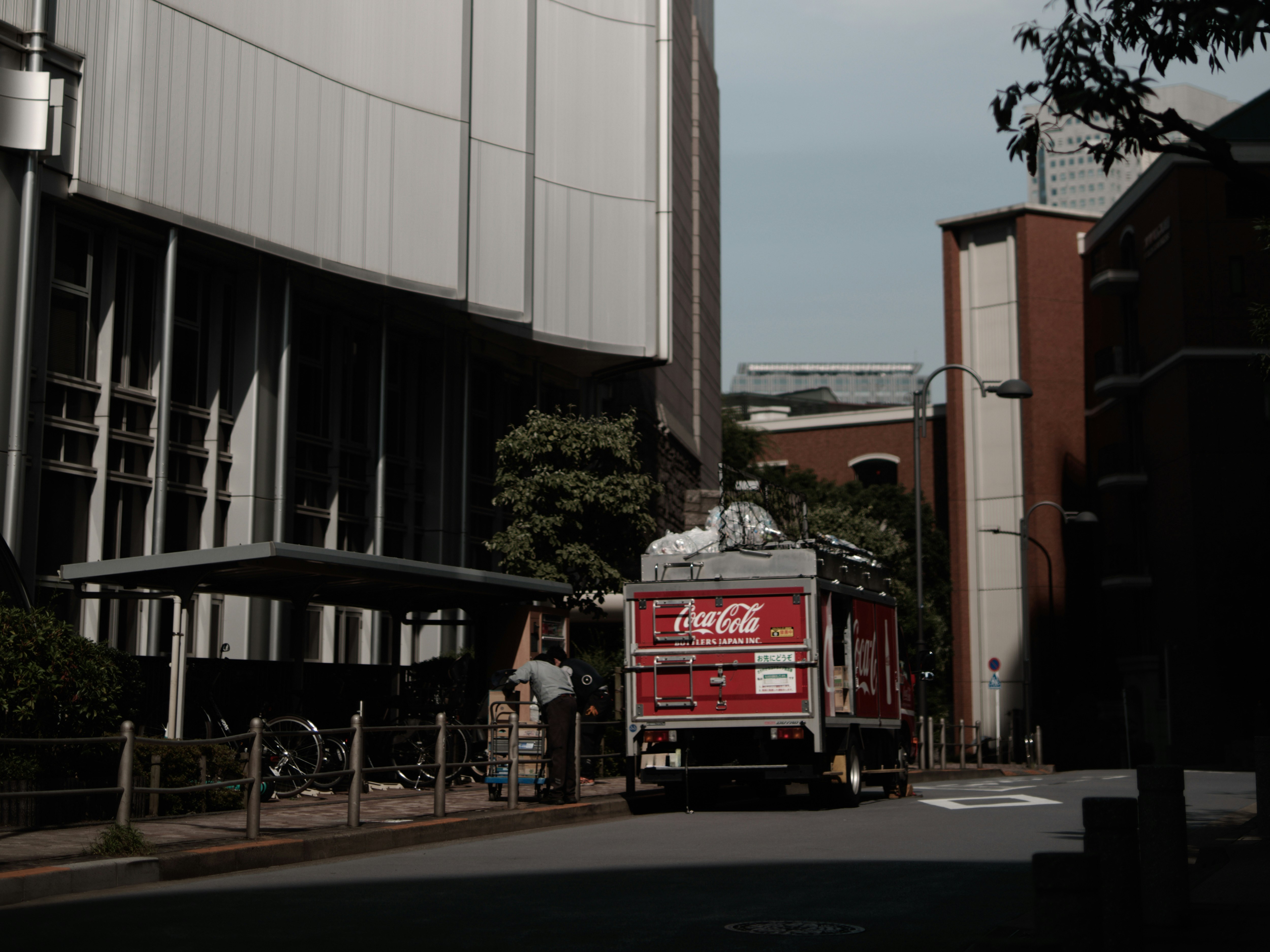 飲み物の自動販売機のある路地でトラックが走る風景