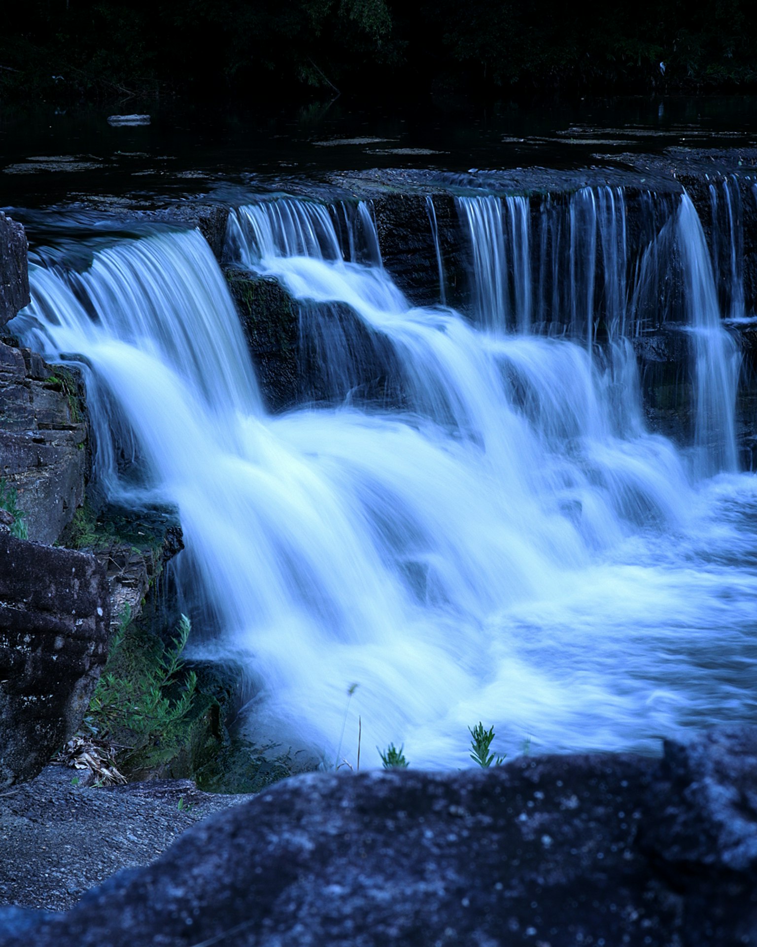 Hermosa cascada fluyendo contra un fondo oscuro