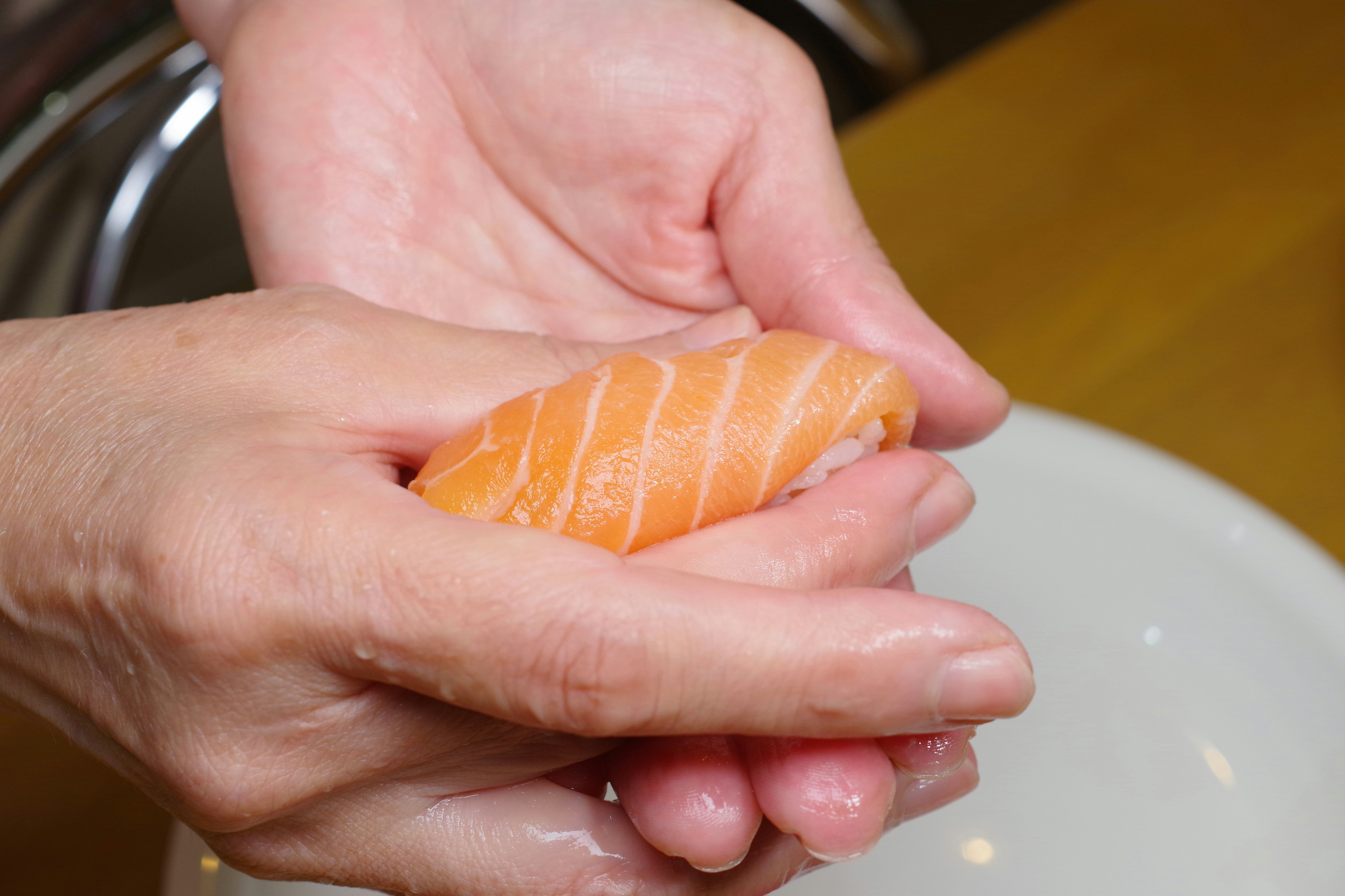 mani che tengono un nigiri al salmone