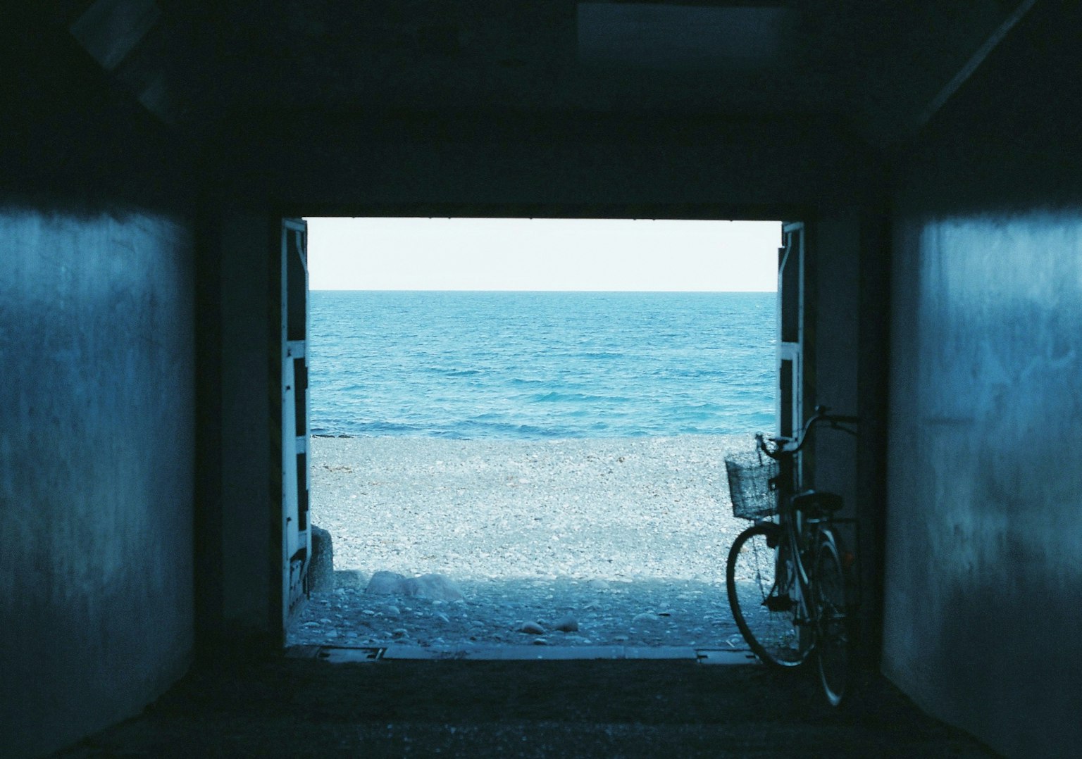 Vélo garé à l'entrée d'un tunnel avec vue sur la mer