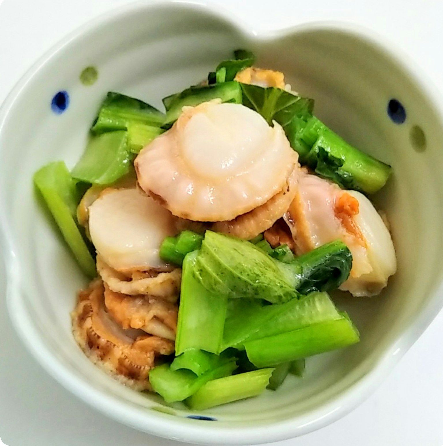 白碗中的扇貝和綠色蔬菜菜餚