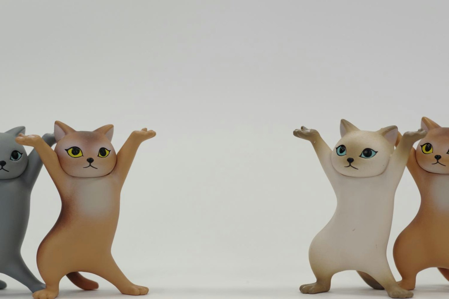 Dua figurine kucing dengan tangan terangkat dalam pose lucu