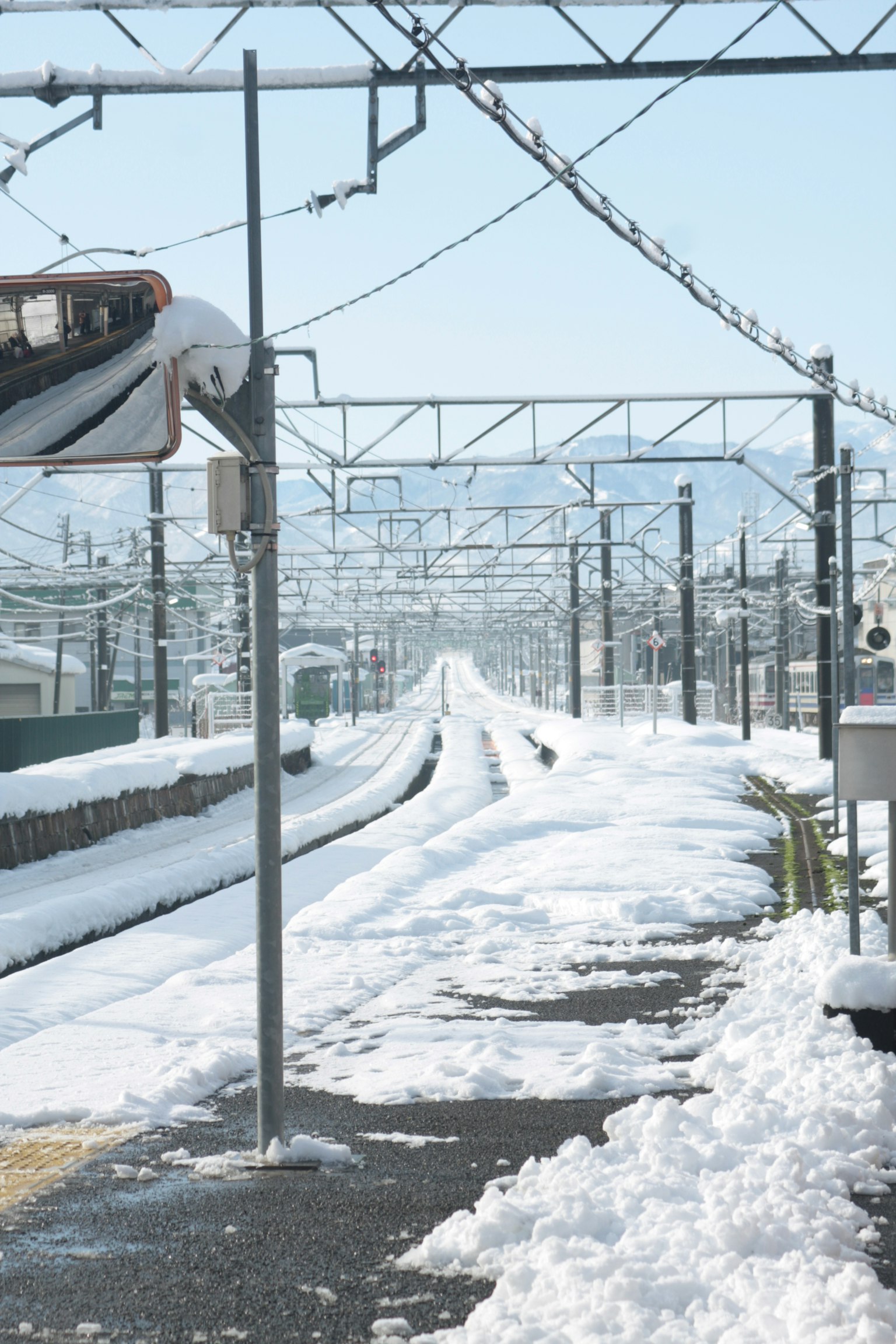 Plateforme de gare recouverte de neige avec des voies visibles