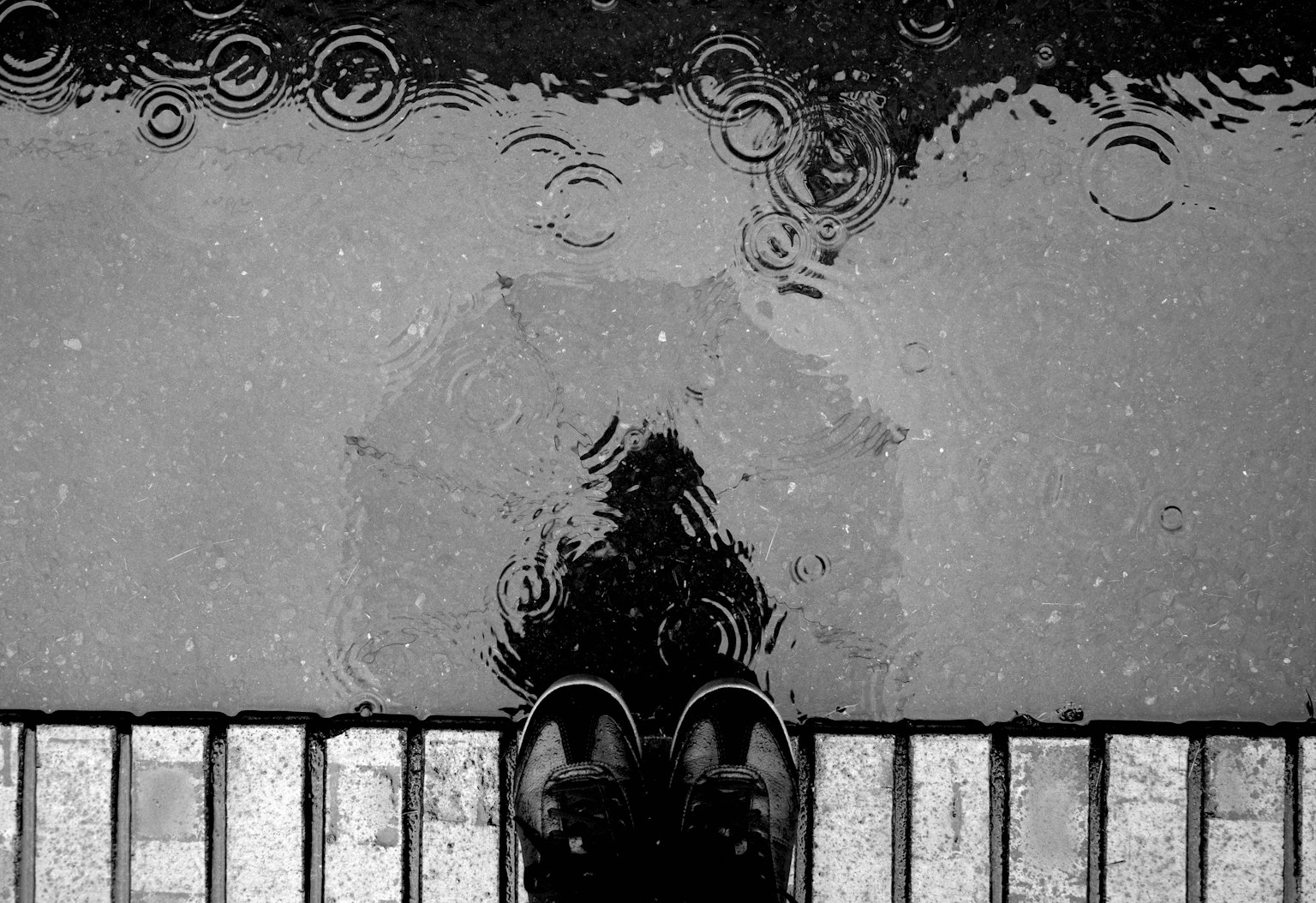 雨中鞋子和傘的反射的黑白圖像