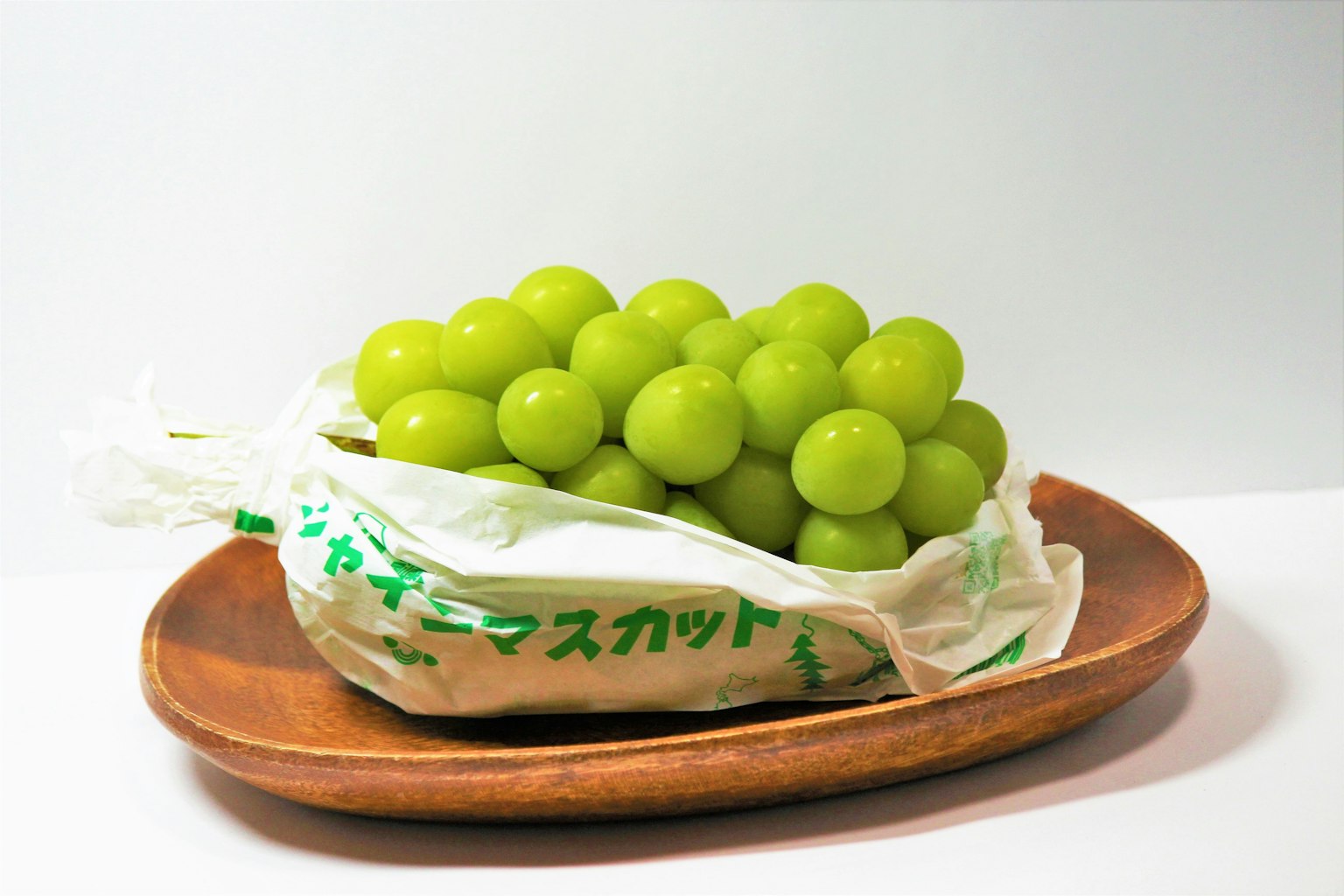 Uva verde in un sac su un piatto di legno
