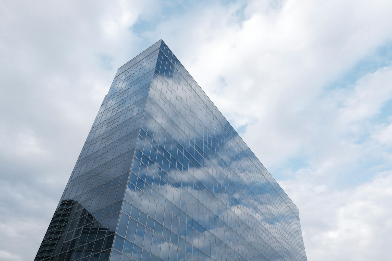 Modern glass building reflecting clouds