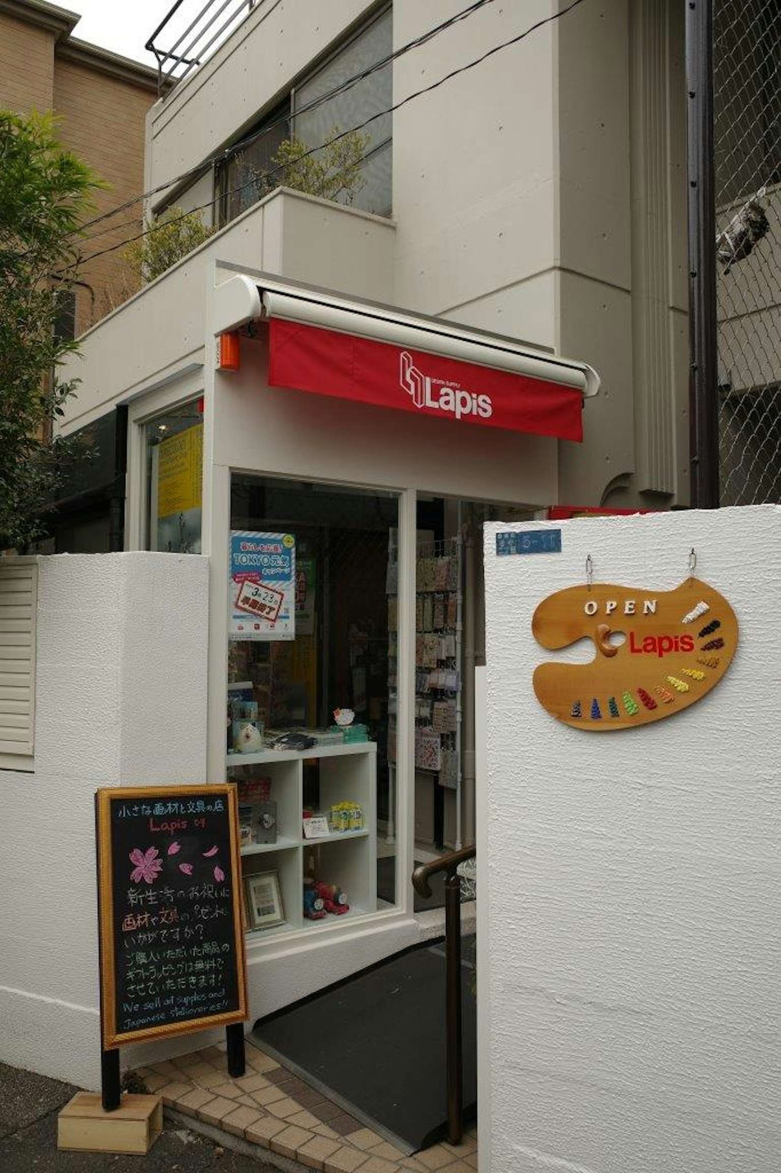 白色墙壁和红色遮阳篷的店面入口，入口处有黑板和木制标志