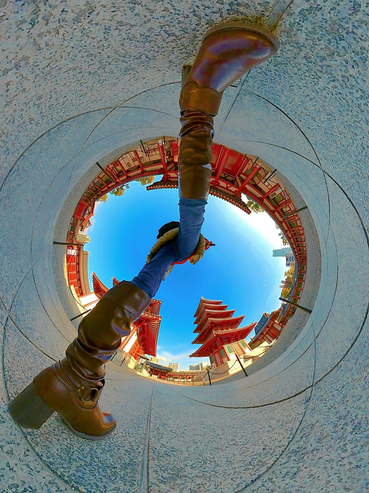 Une vue en perspective à travers une ouverture circulaire montrant un paysage et les jambes d'une personne