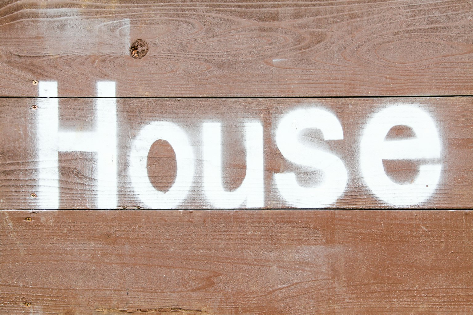 White spray-painted word House on a wooden background