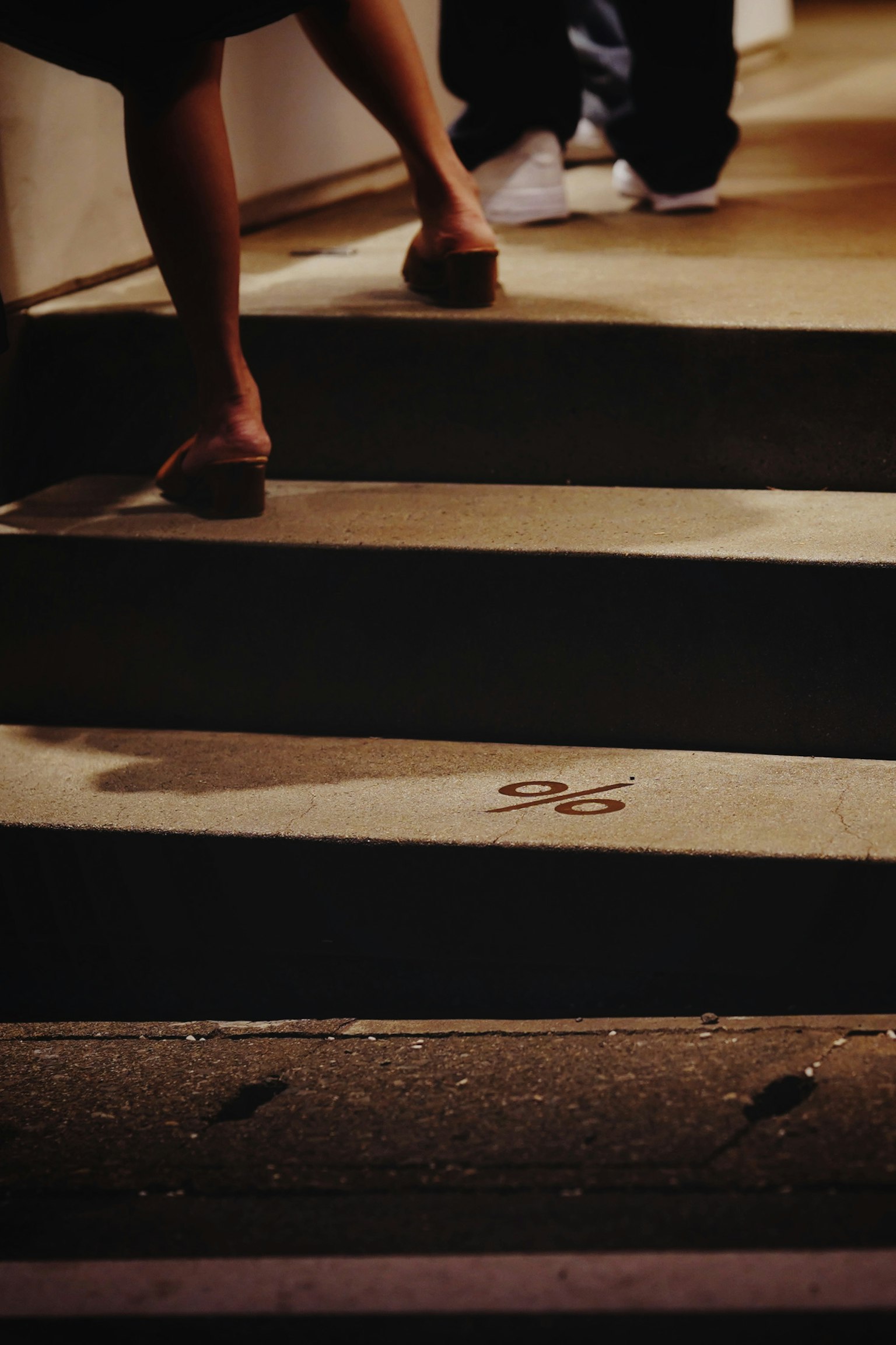 Close-up of feet on stairs with shadows in a nighttime setting