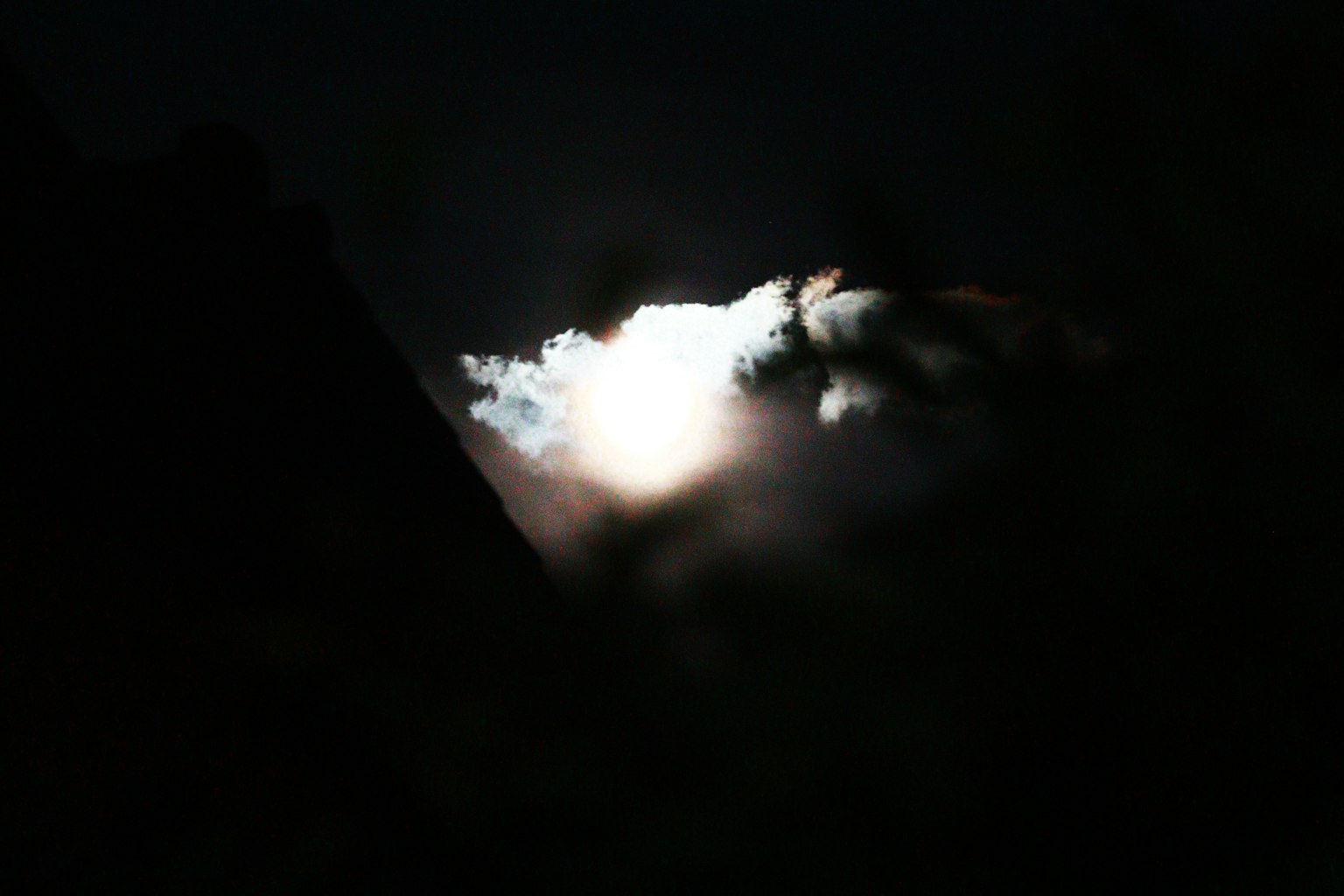Luna parzialmente coperta da nuvole in un cielo notturno scuro