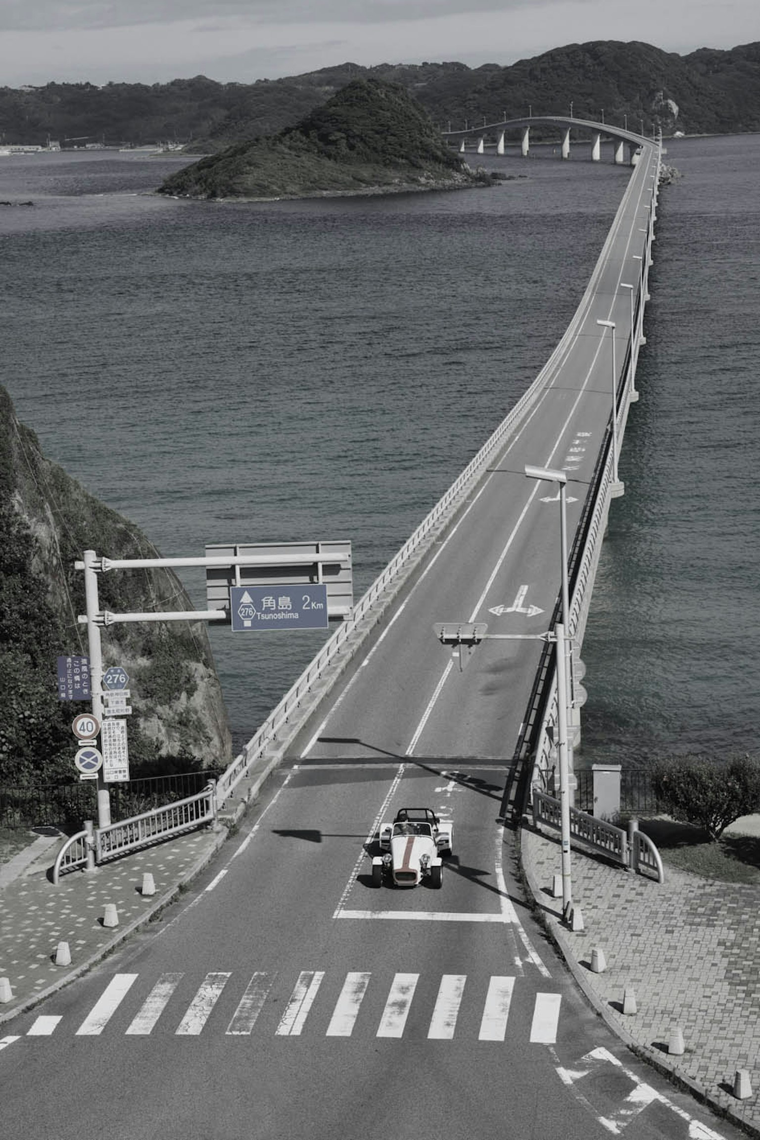 一座长桥横跨海面，路上有一辆车
