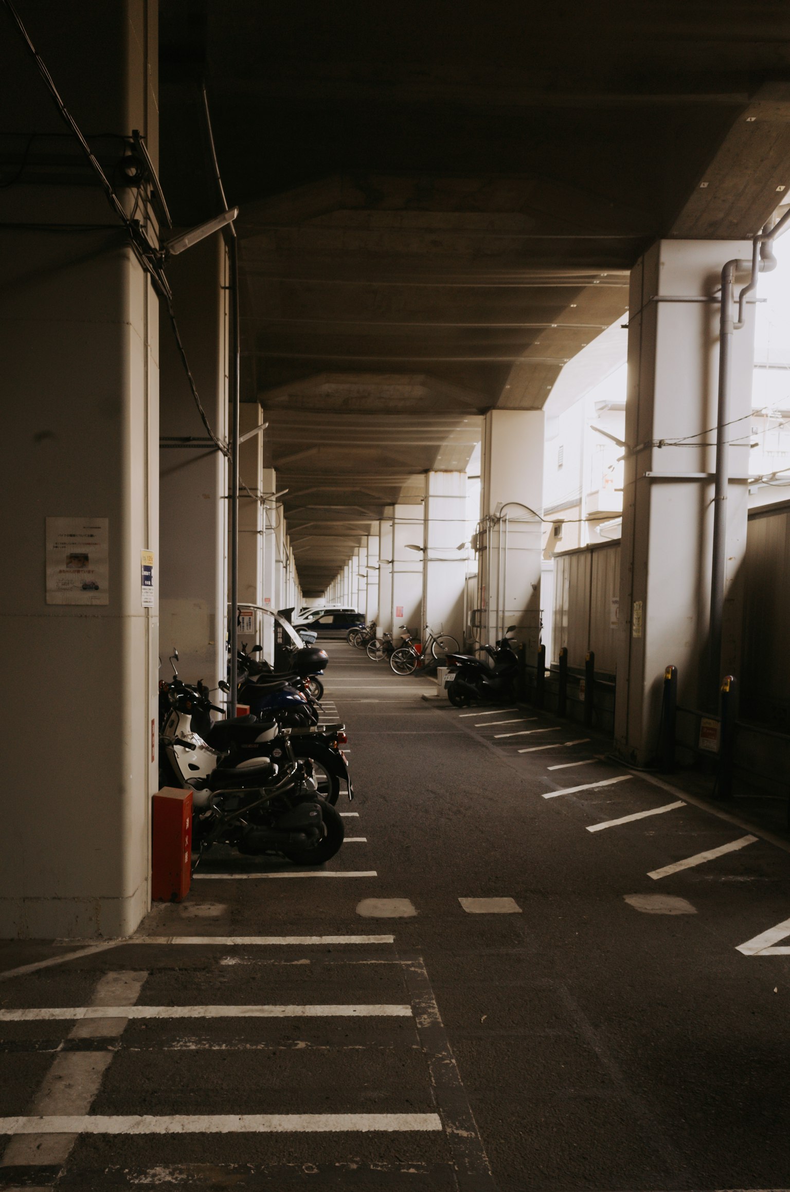 ภาพของทางเดินในที่จอดรถที่มีมอเตอร์ไซค์และรถยนต์จอดอยู่
