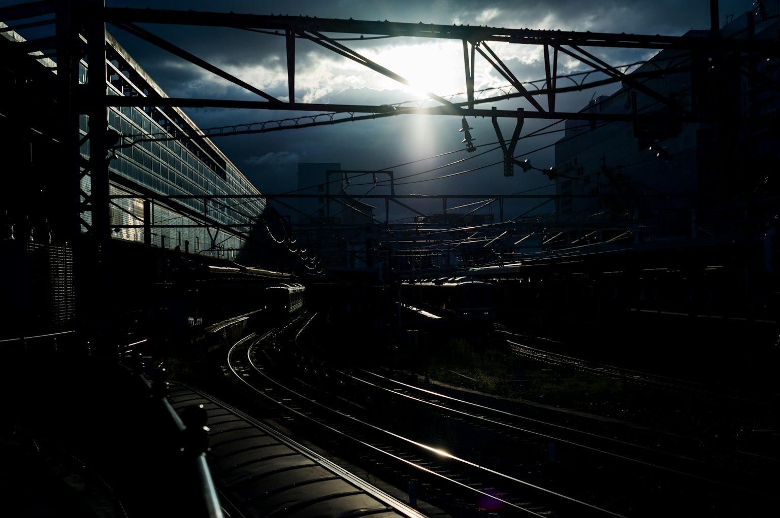 A dark railway scene illuminated by sunlight