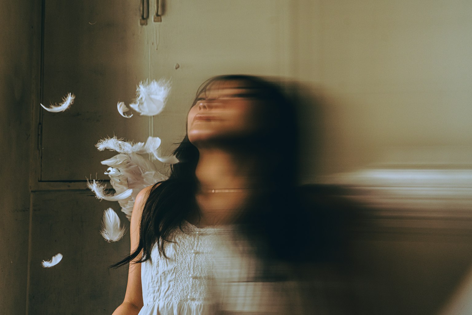 羽毛が舞う中で動きのある女性の姿