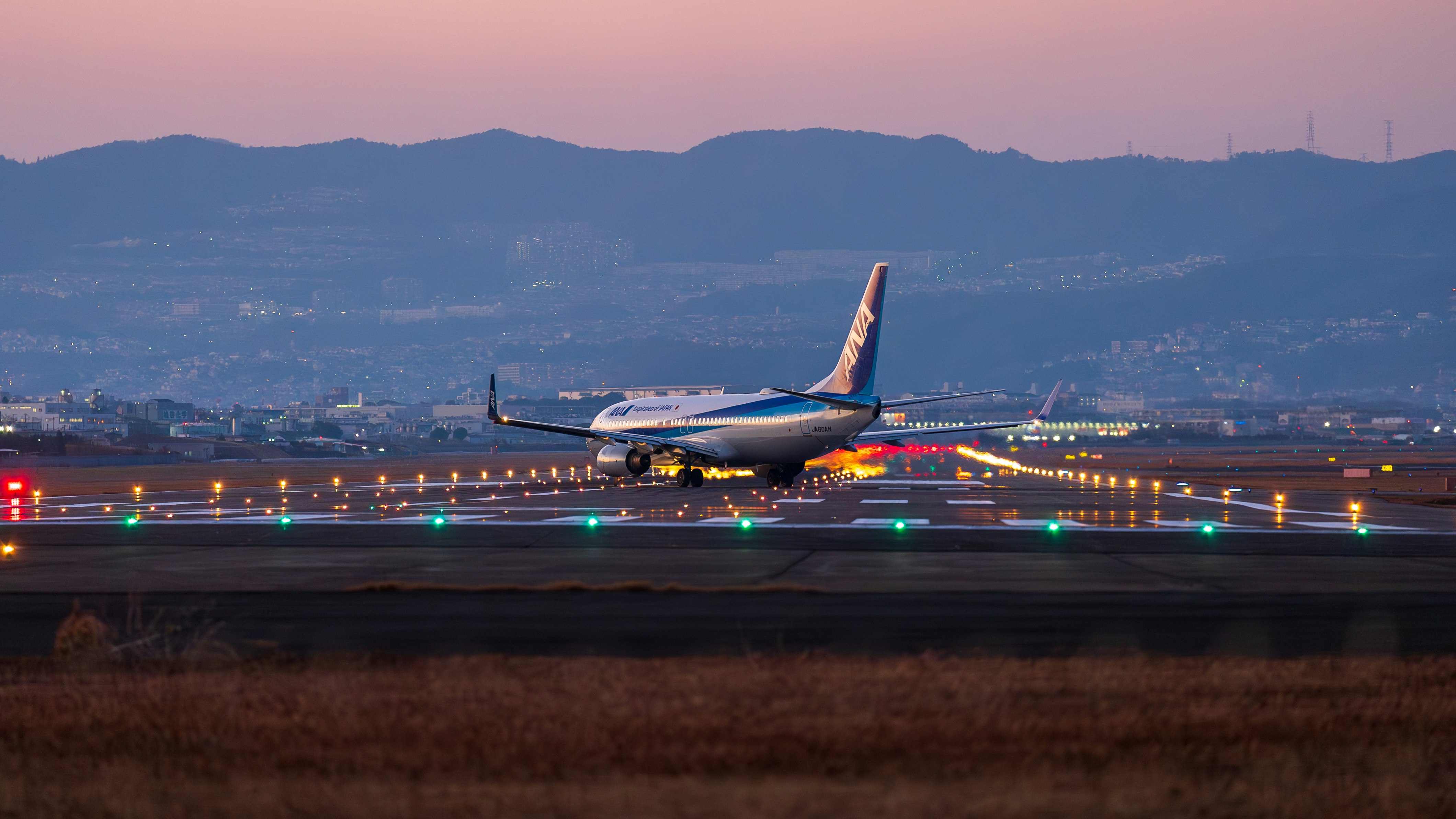 夕暮れの滑走路を離陸する旅客機のある空港の風景