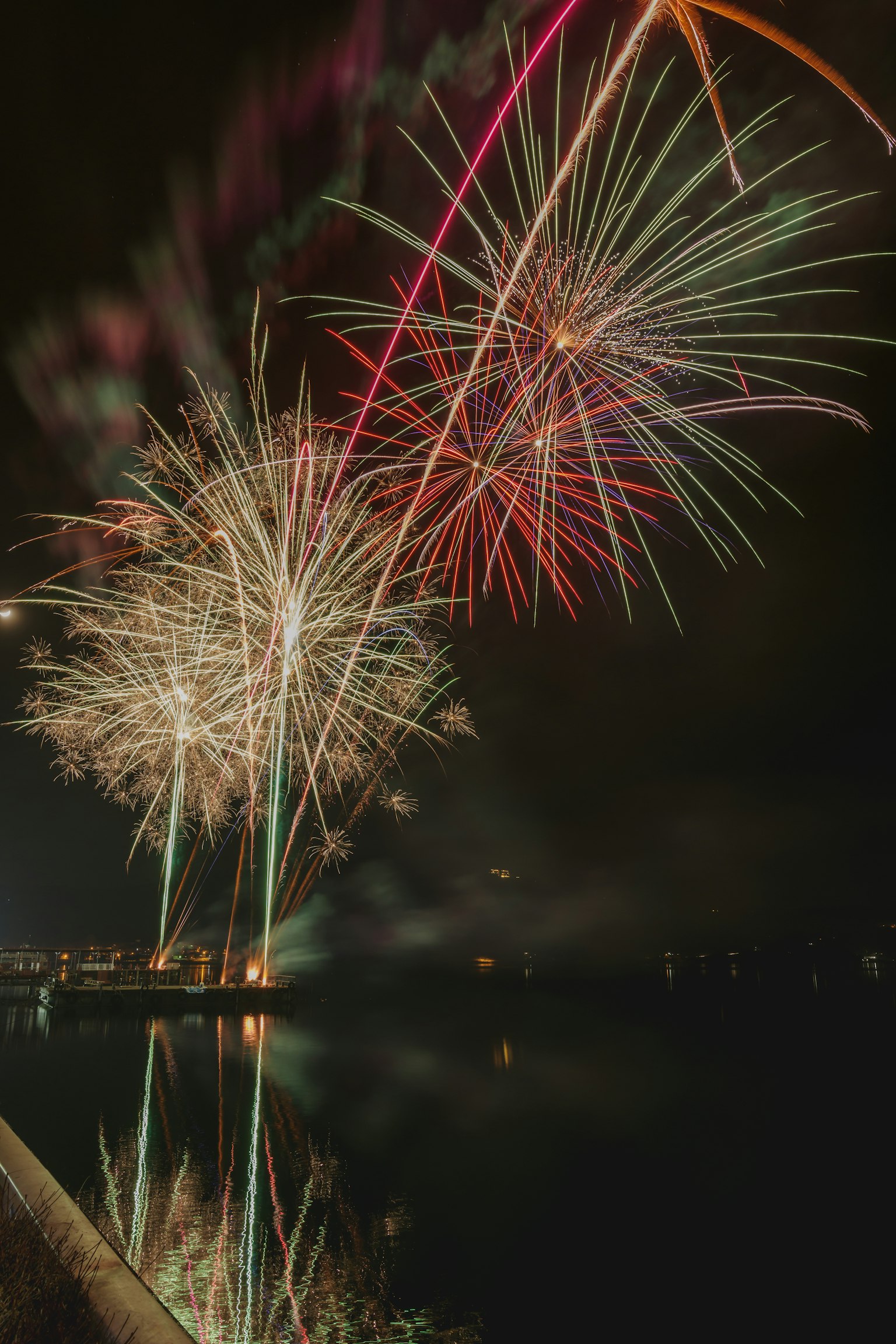 Colorful fireworks lighting up the night sky with reflections in water