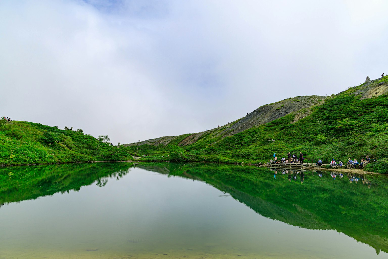 Vista escénica de un lago rodeado de vegetación y colinas