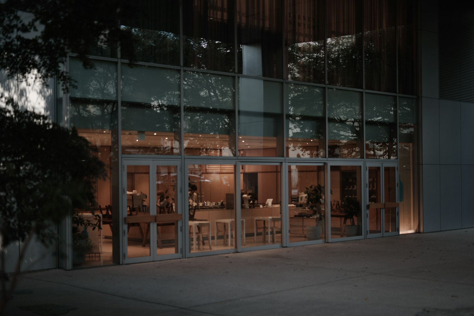 Vue nocturne de l'intérieur d'un café visible à travers une entrée en verre d'un bâtiment