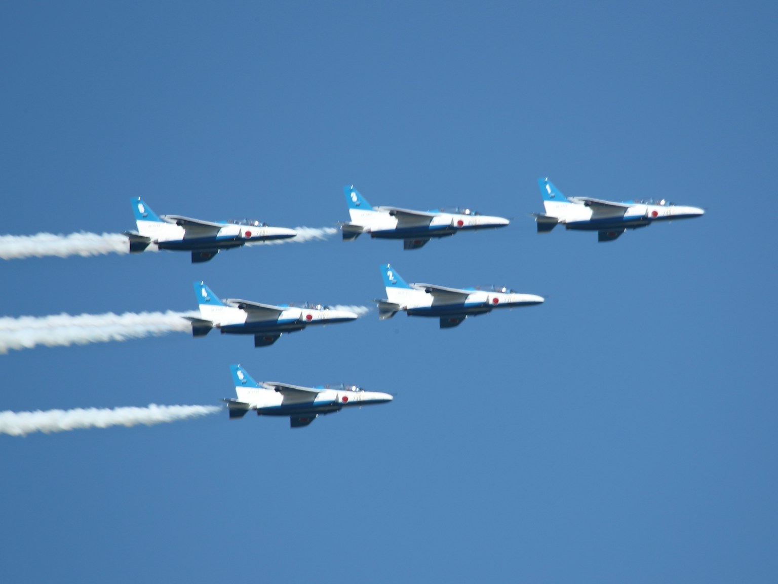 Formation von sechs Kampfflugzeugen, die in einem klaren blauen Himmel fliegen