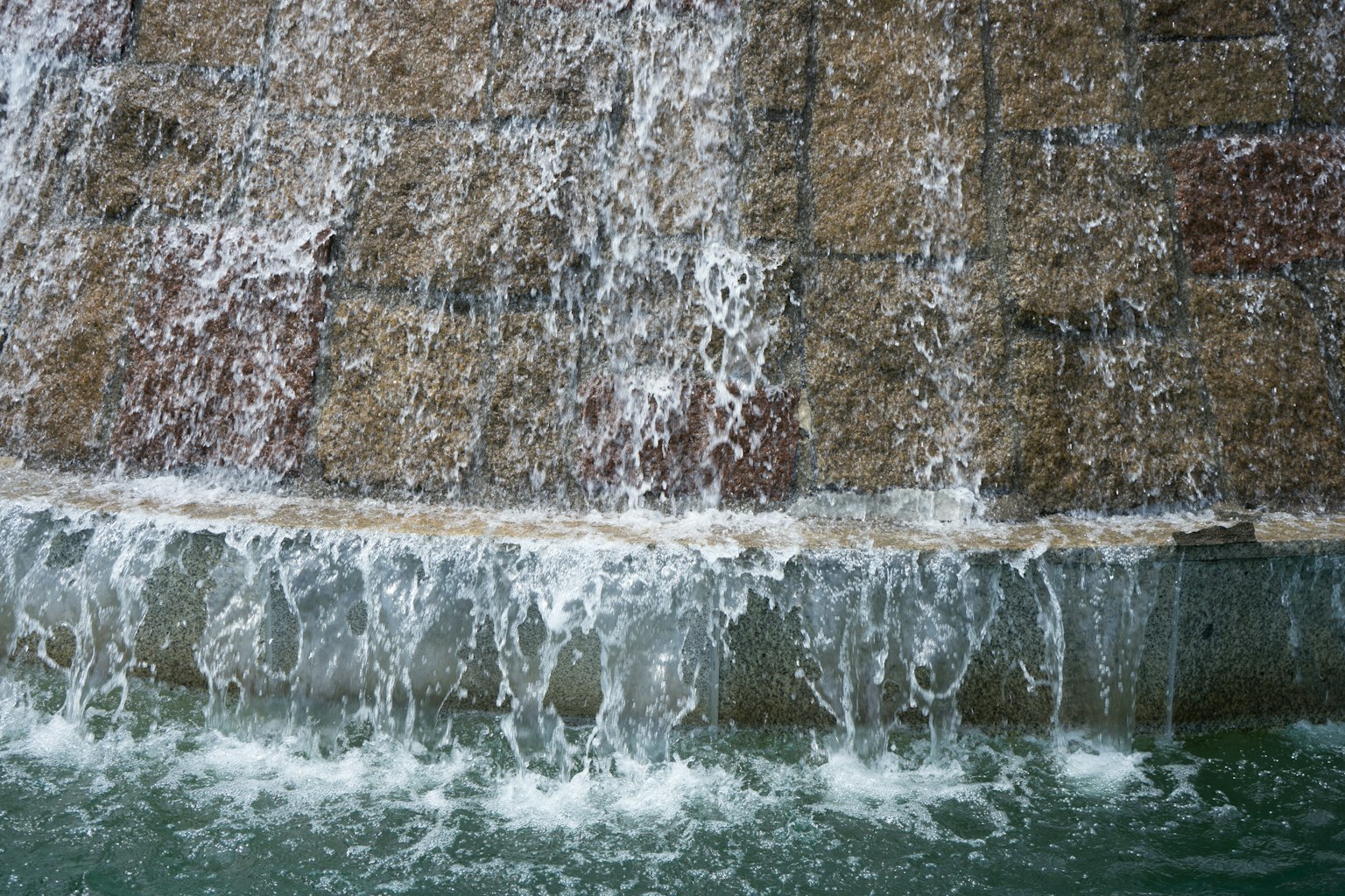Primo piano di una cascata che scorre su un muro di pietra con schizzi