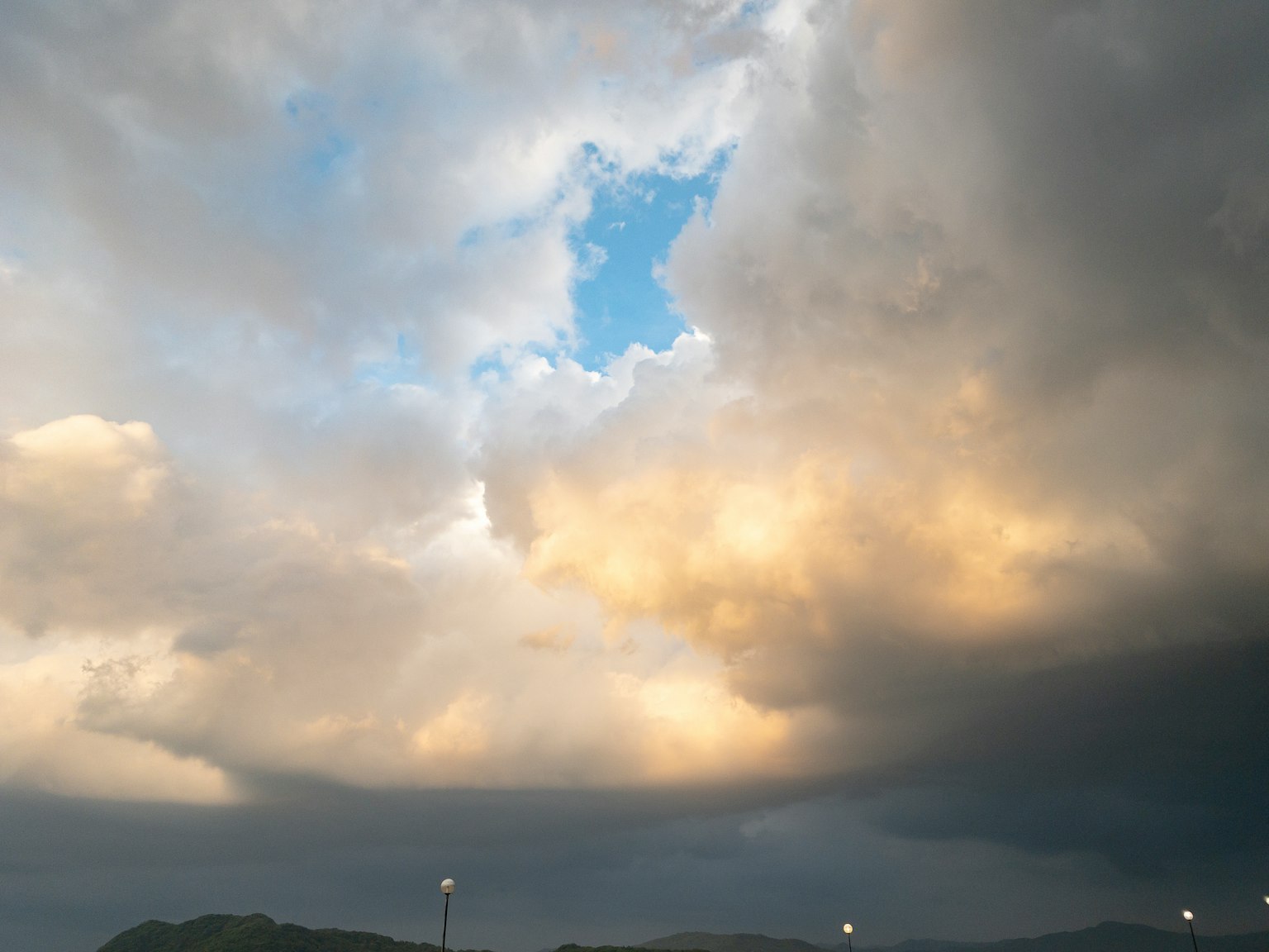 Ouverture dans des nuages sombres révélant un ciel bleu et une lumière dorée