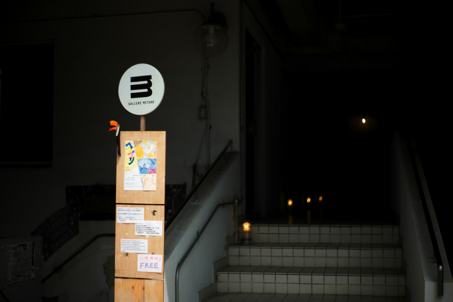 階段の前に立つ木製の看板とロゴのあるサイン