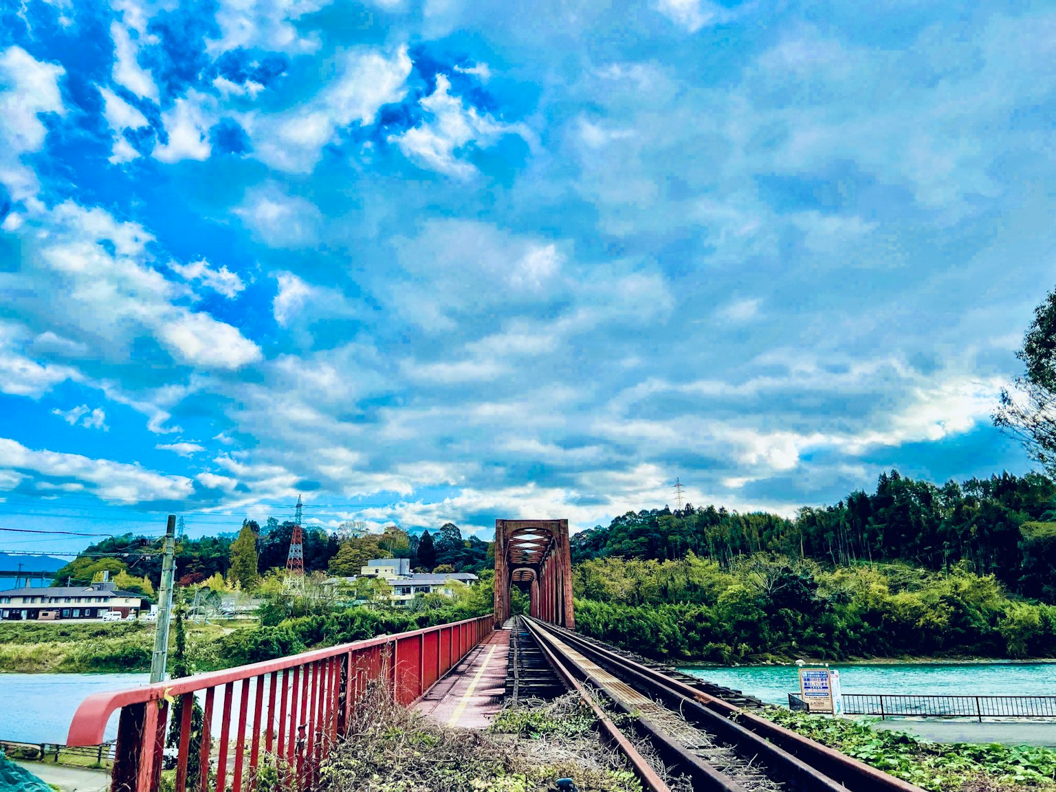 Ponte ferroviario rosso e binari sotto un cielo blu