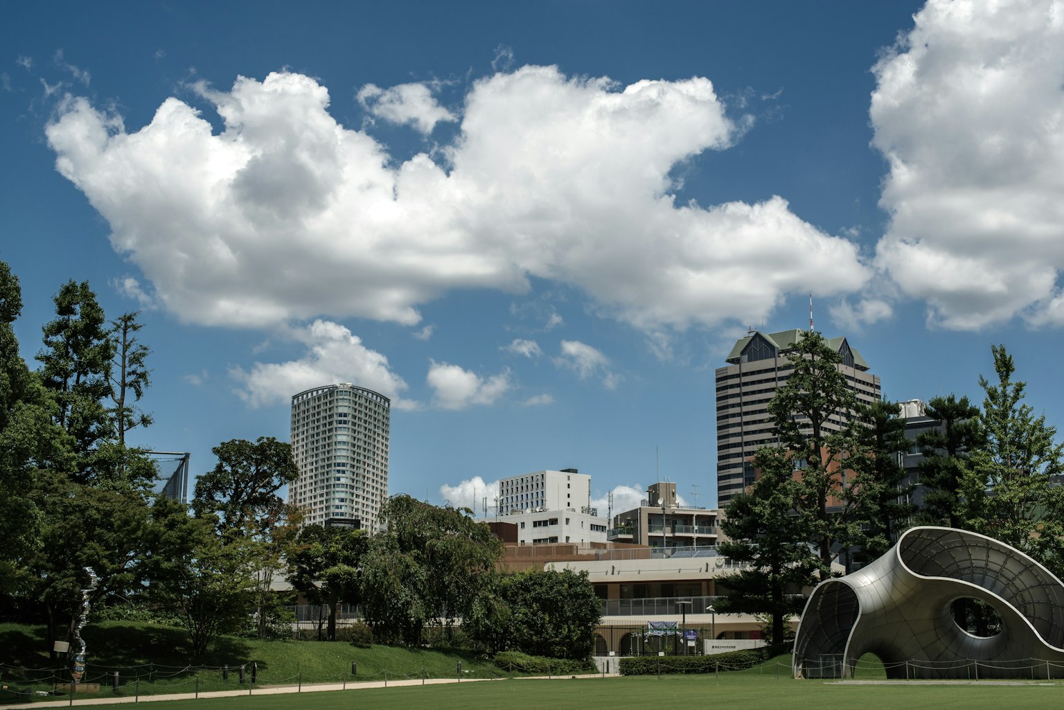 城市公园场景，蓝天白云，高楼大厦和现代艺术雕塑