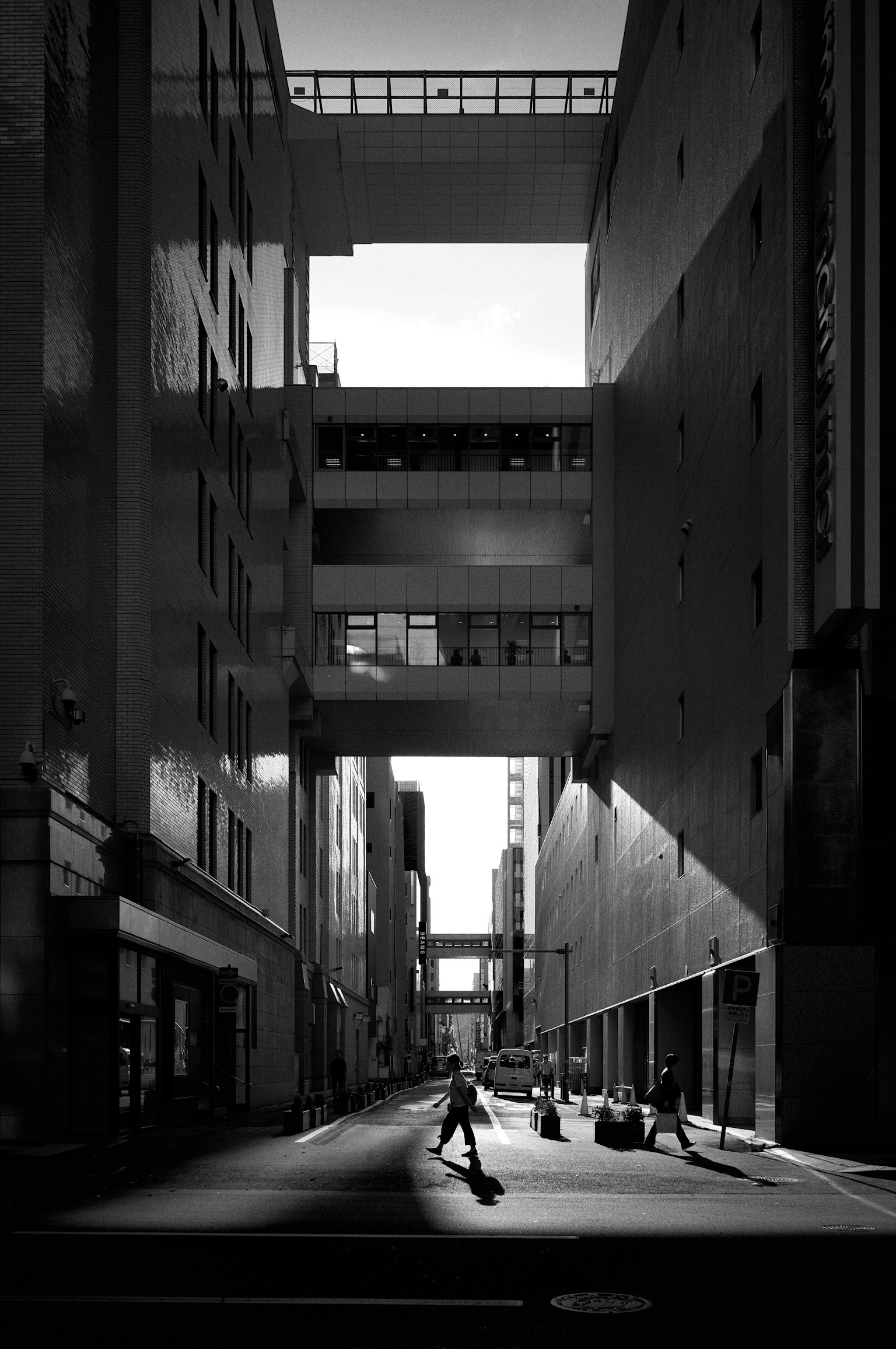 黒と白の都市風景の中で人々が歩く狭い通り