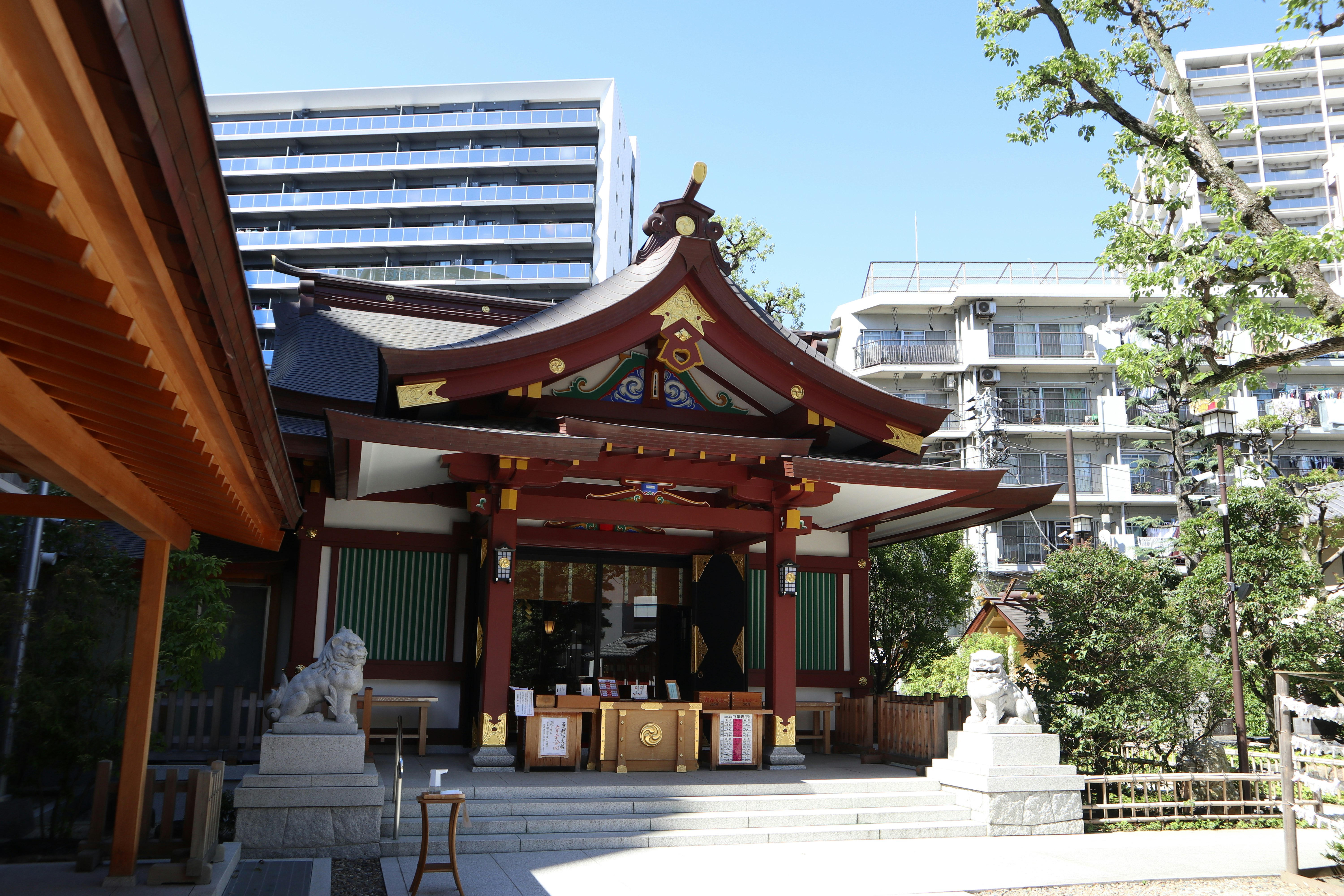 神社手水舍與石像，背景有城市建築