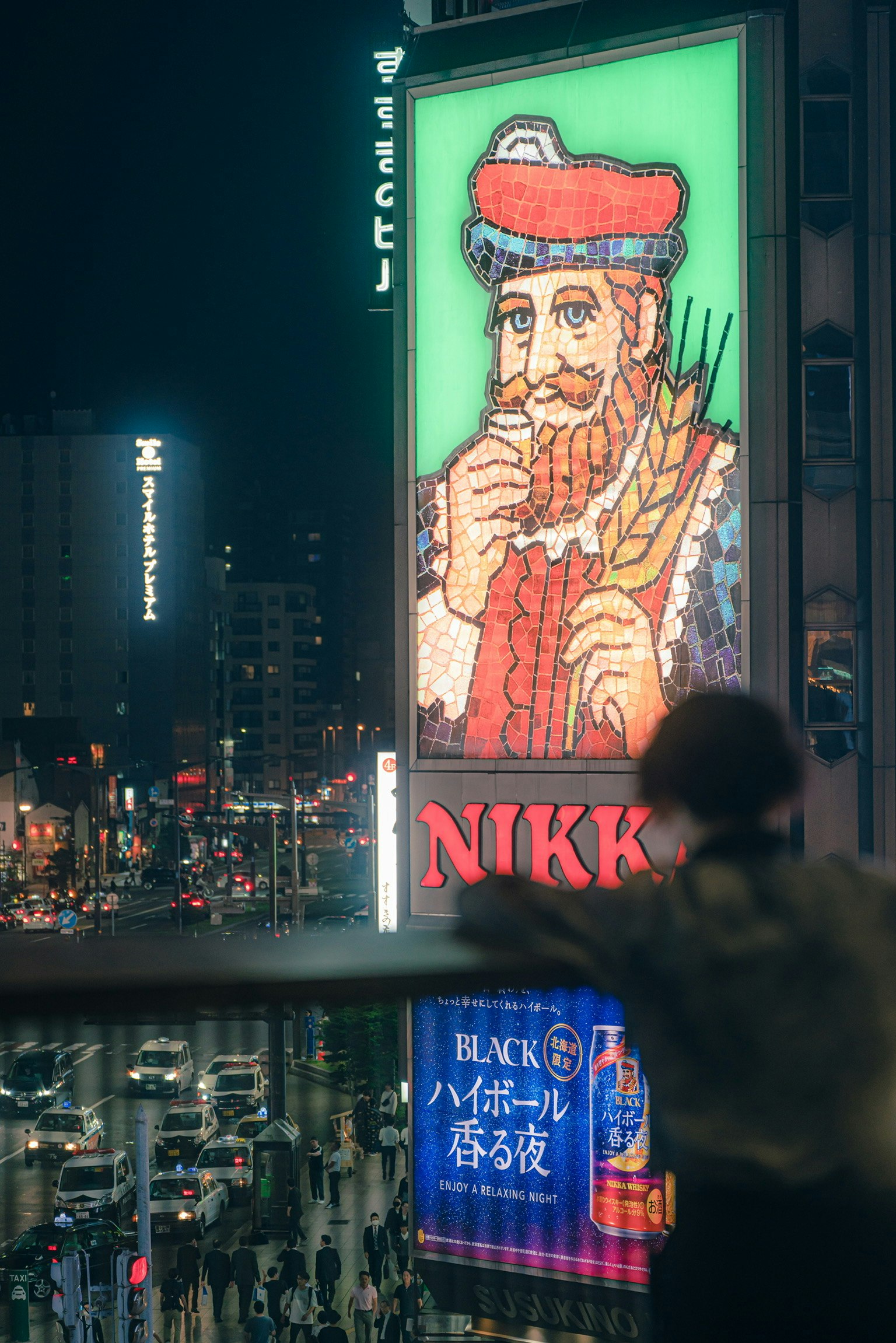Vibrant cityscape at night featuring a large NIKKI neon sign with a bearded man