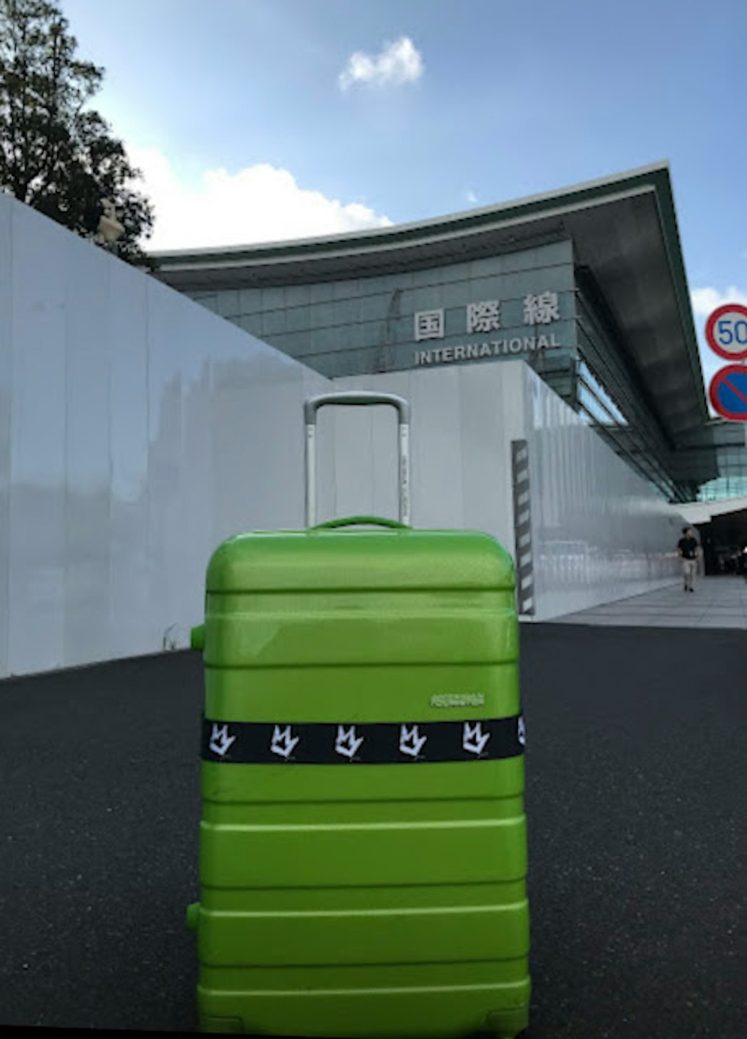Green suitcase in front of a modern building