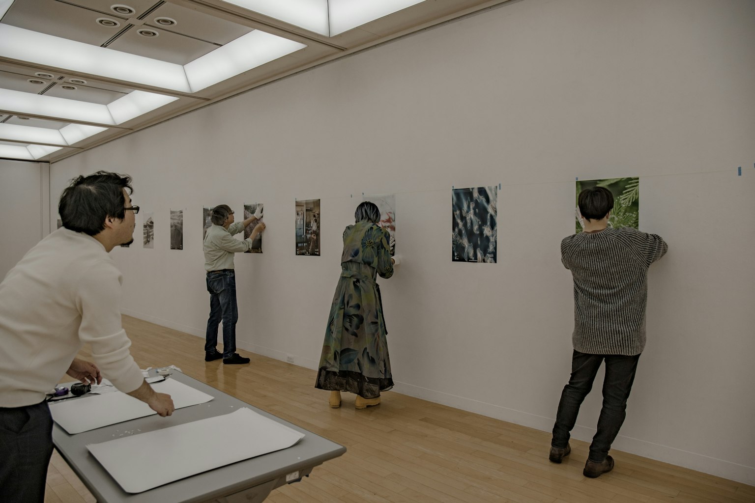 People viewing artworks in an art gallery Various pieces displayed on the wall