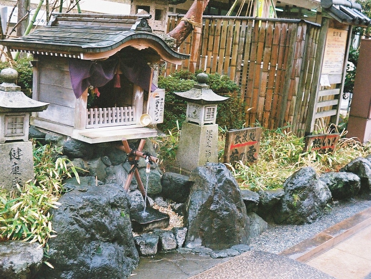 竹垣と石の手水鉢がある寺院の参道