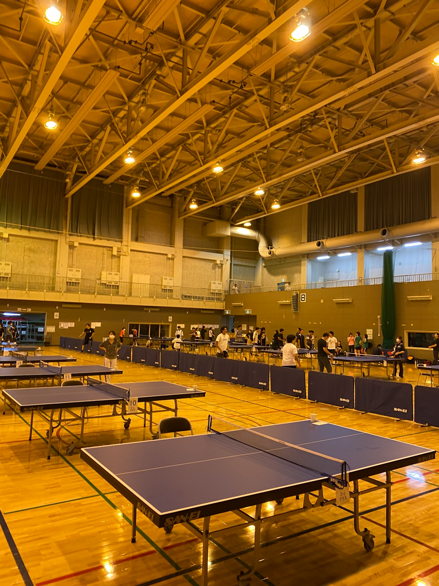 Gimnasio espacioso con filas de mesas de tenis de mesa y espectadores