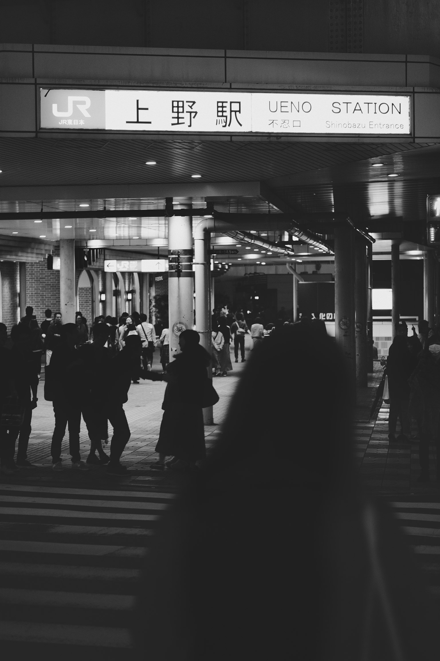 上野駅の入り口で人々が行き交うモノクロ写真
