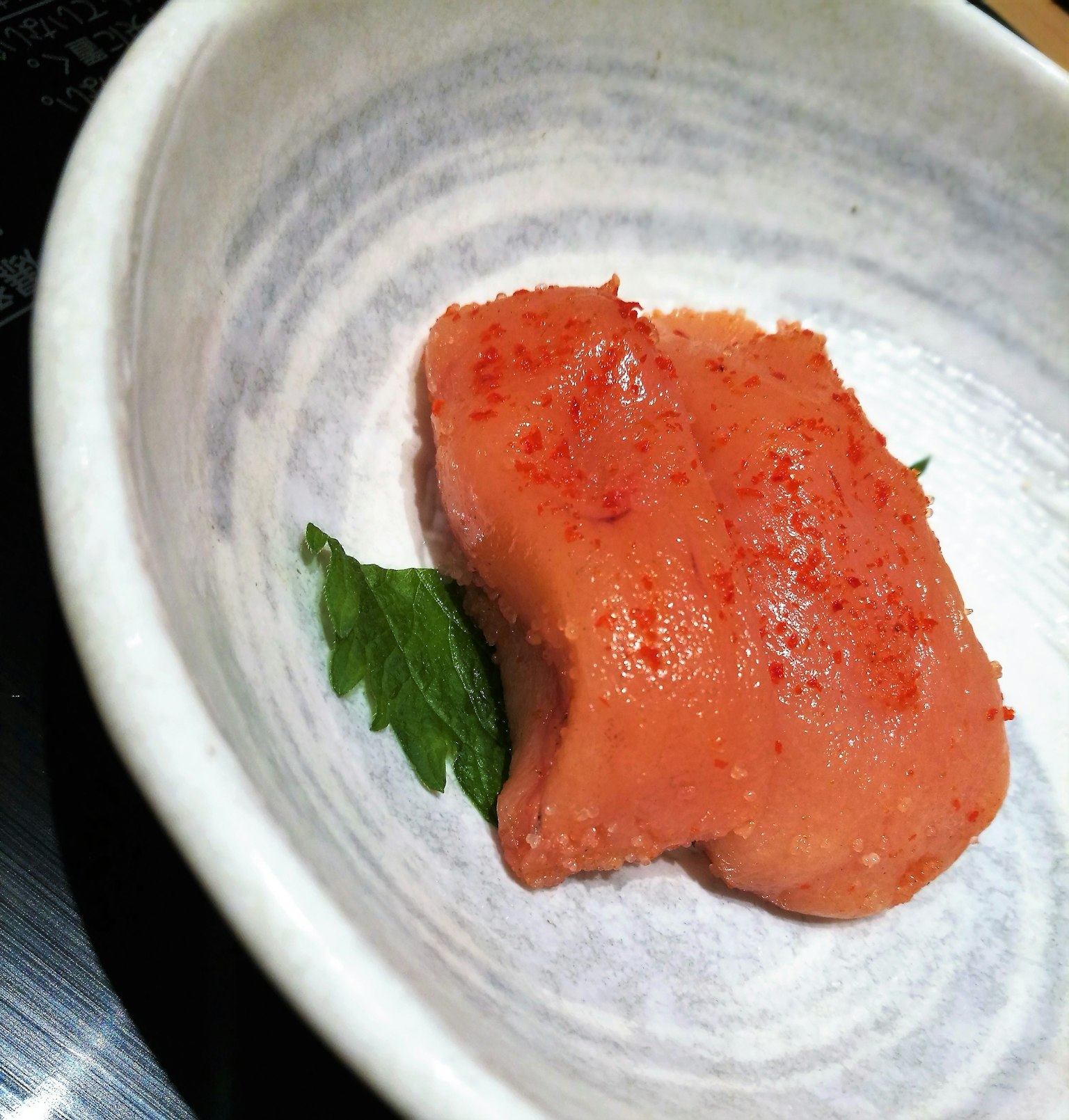 Bright orange fish roe placed on a plate with a green leaf