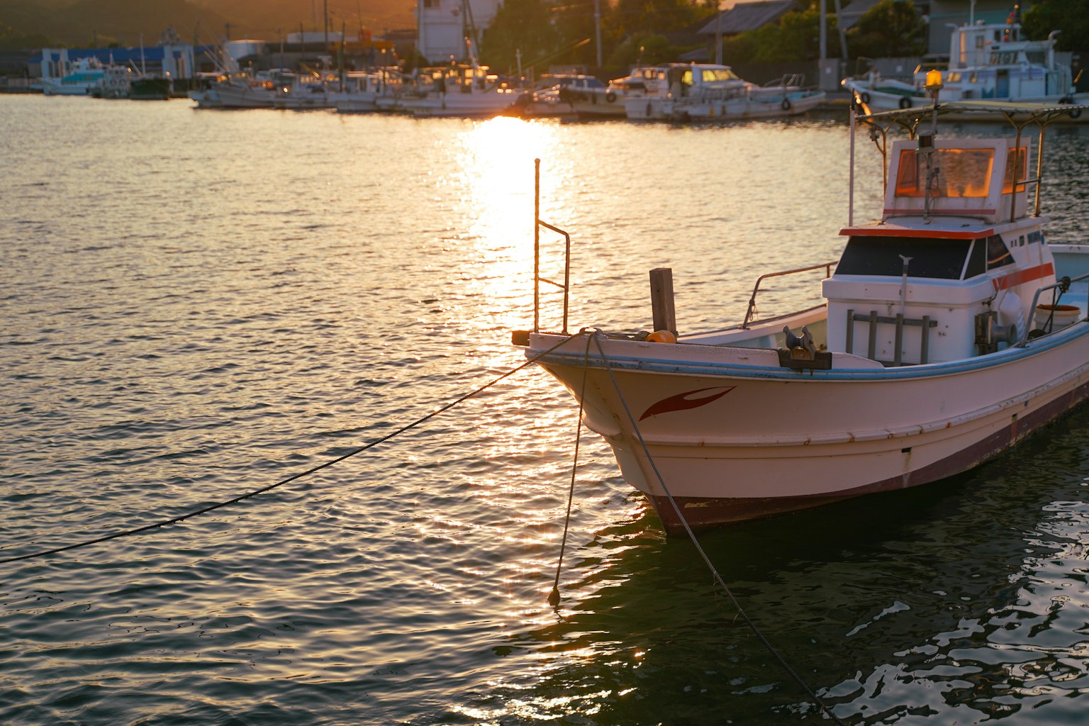 Peschereccio ormeggiato nel porto con riflessi del tramonto sull'acqua