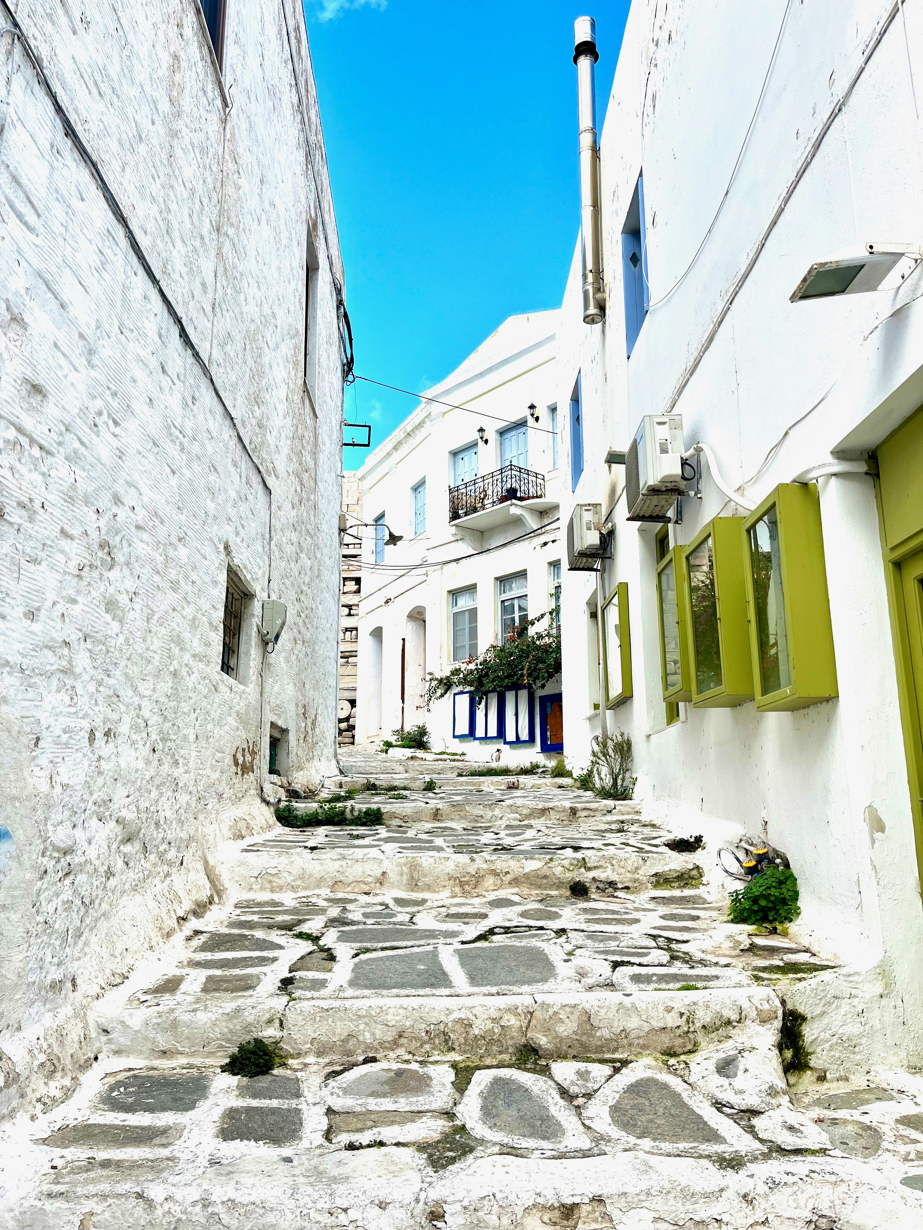View down a narrow alley with white walls and stone steps