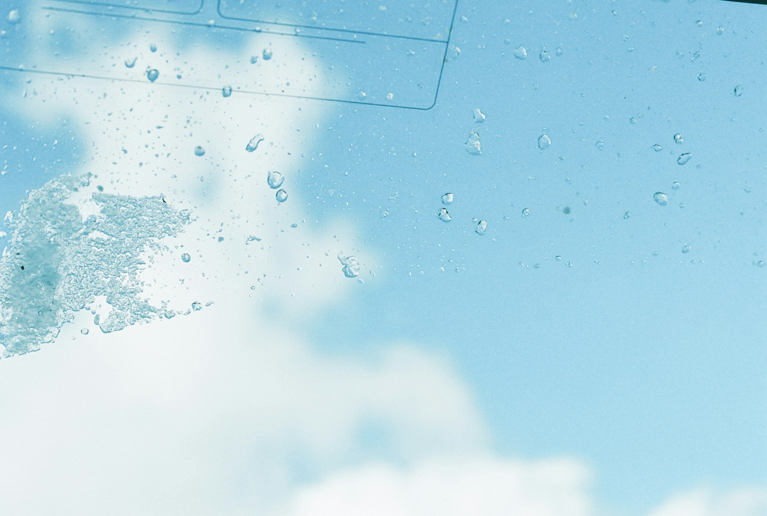 Glas mit Wassertropfen vor blauem Himmel