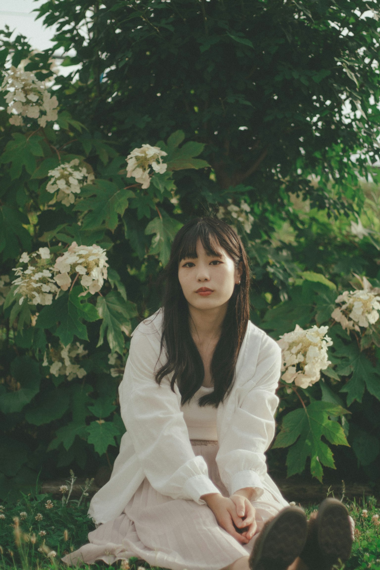 一位穿著白色服裝的女性坐在花前