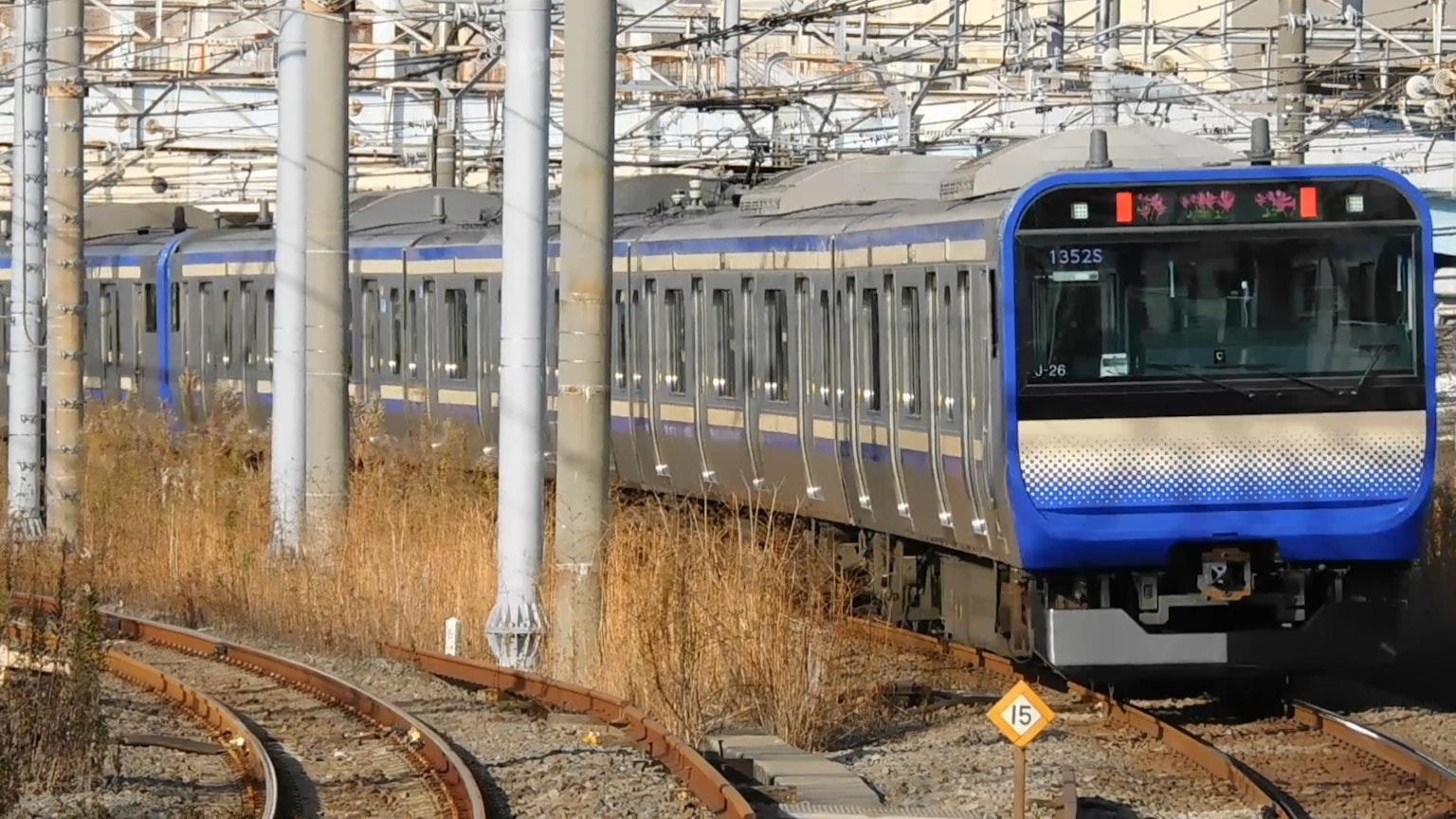 藍色火車在彎曲的軌道上，背景有鐵路電線桿