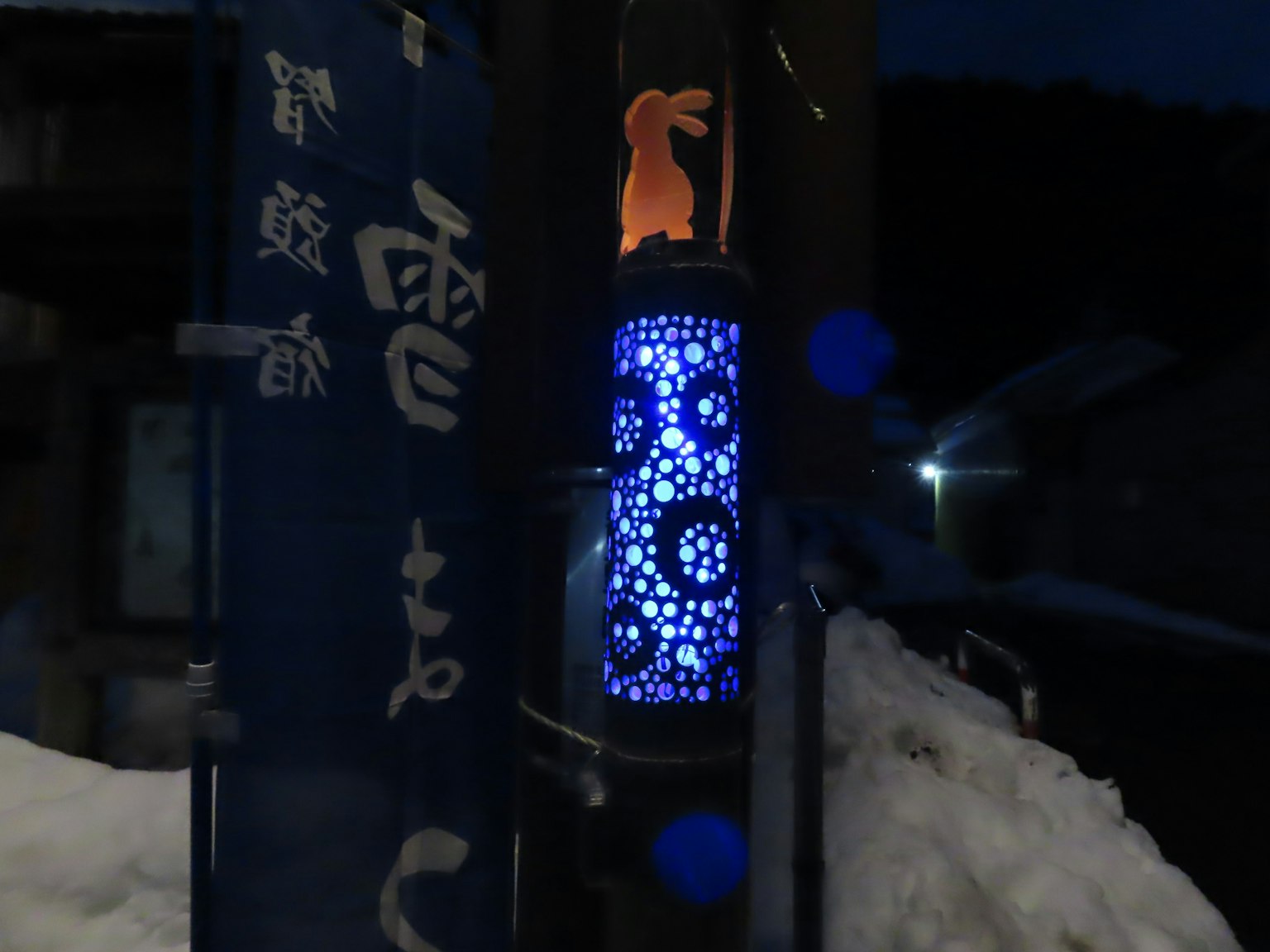 Beleuchtete blaue Lampe mit floralen Mustern und einer Hasensilhouette im Schnee
