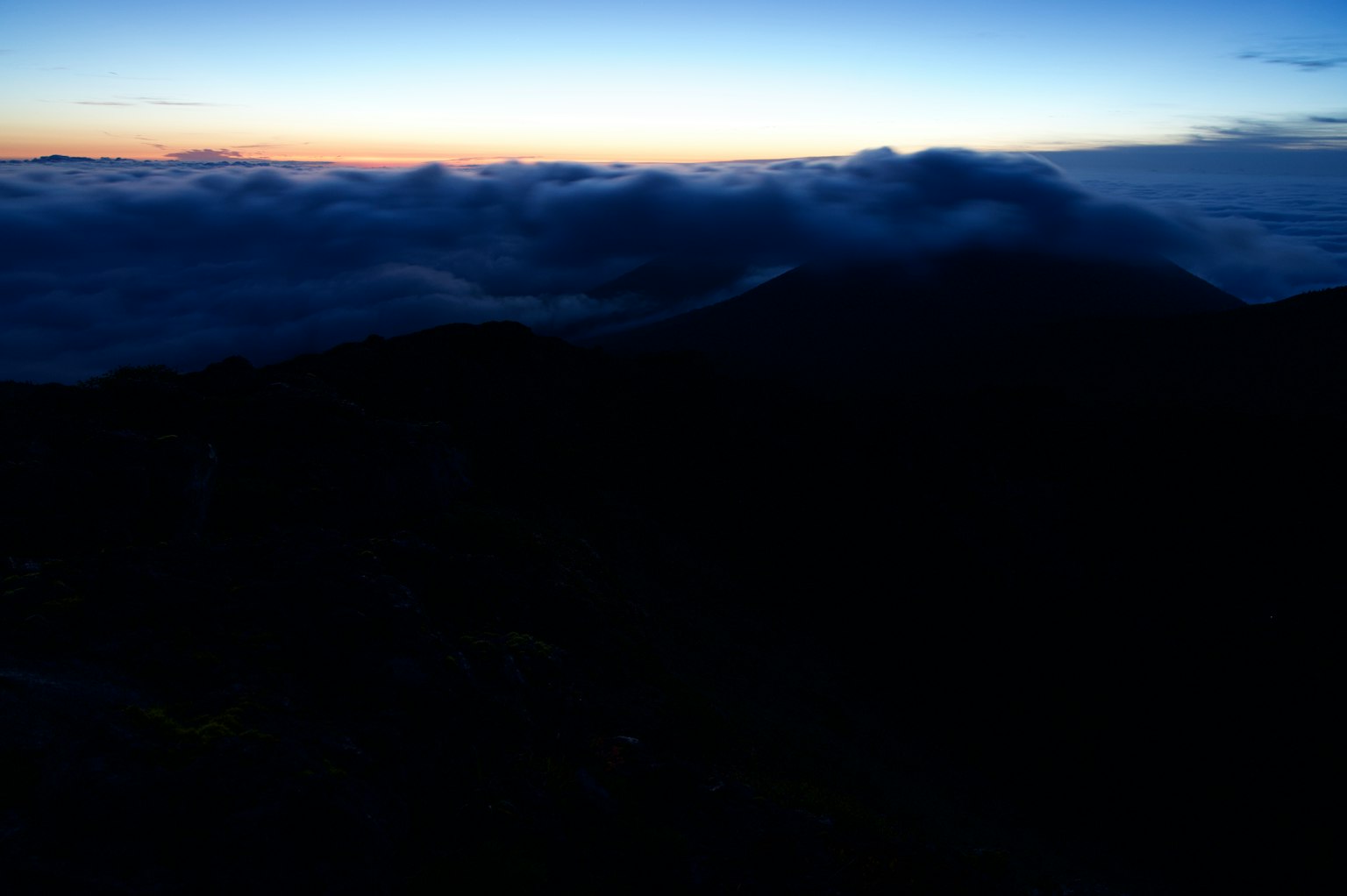 Silhouette von Bergen über einem Wolkenmeer mit Morgenlicht