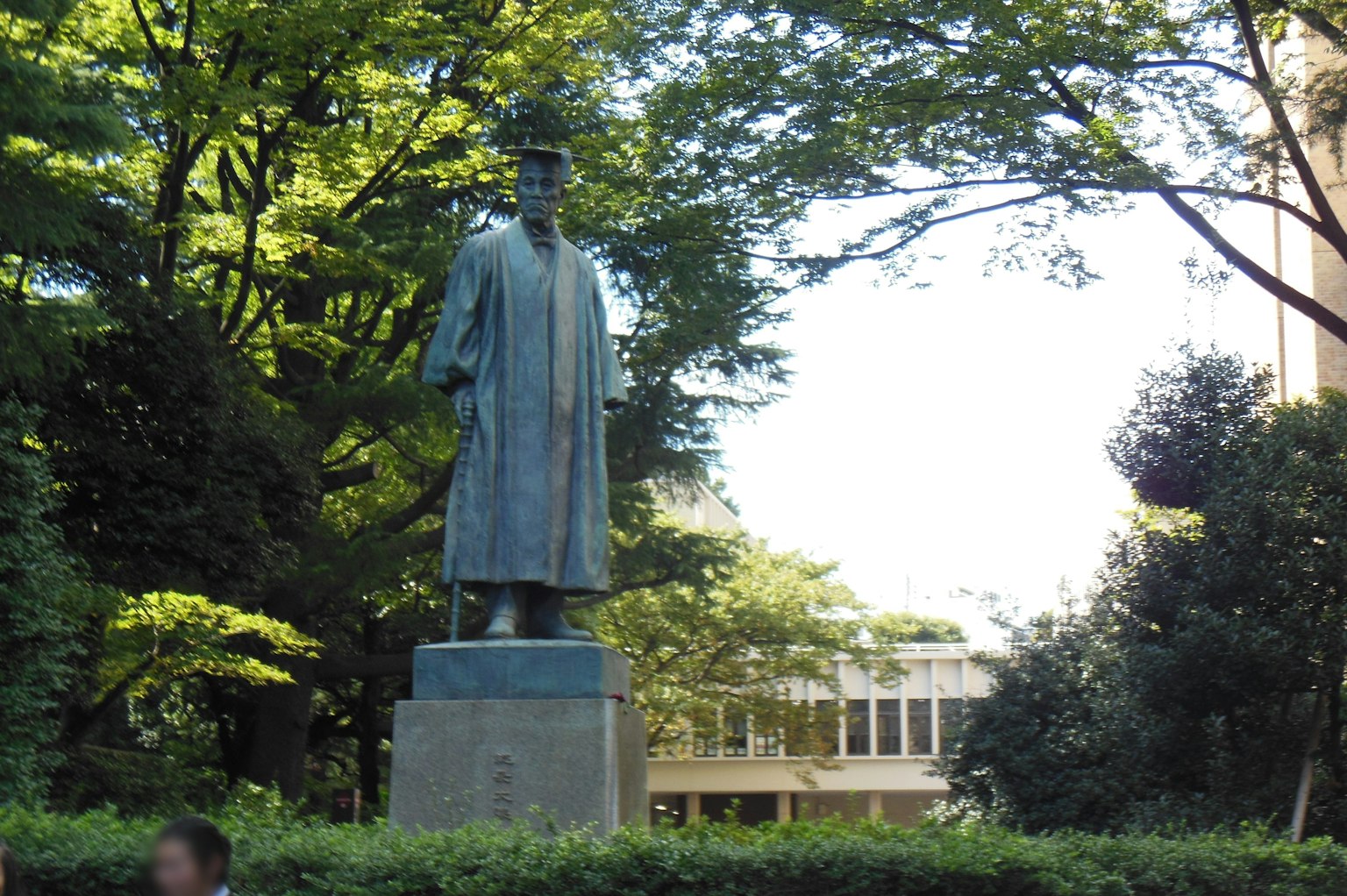 Statua in bronzo che si erge in un parco lussureggiante circondata da alberi
