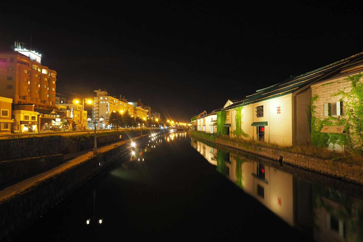 Vista nocturna de un canal con edificios y reflejos