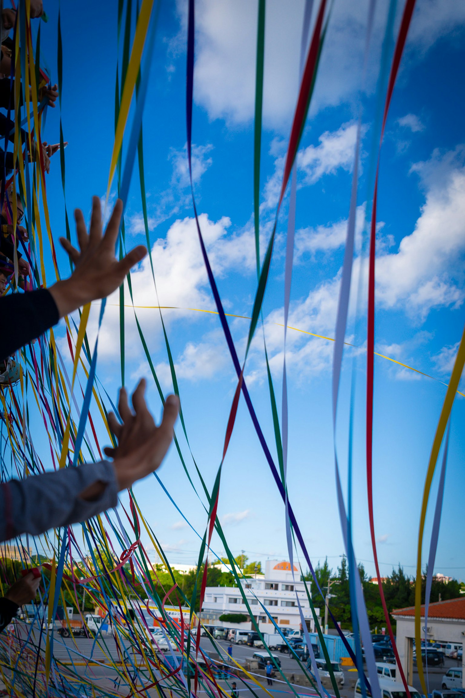 青空とカラフルなリボンが見える手の近くの画像