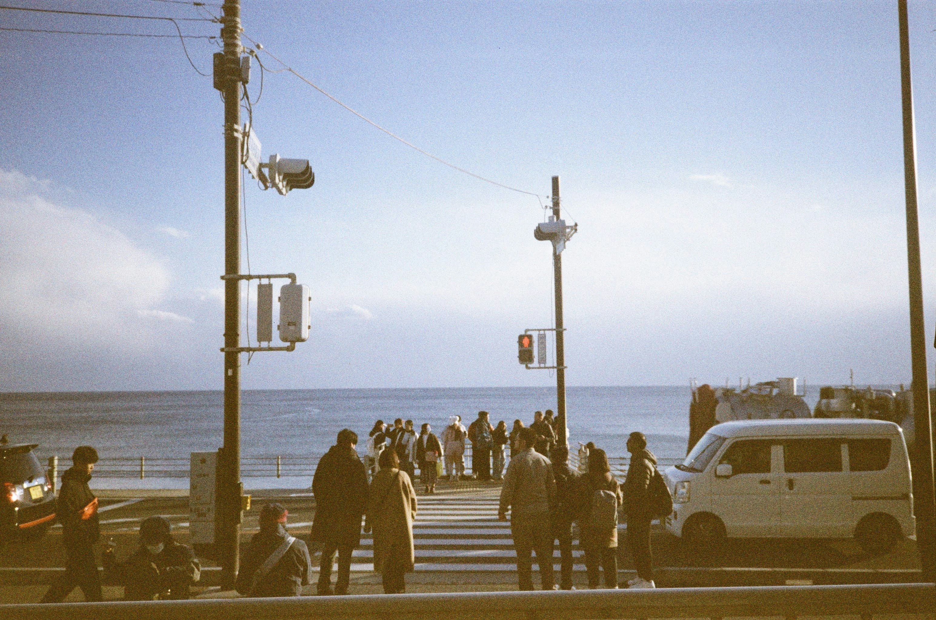 海沿いの遊歩道を歩く人々と車のある風景