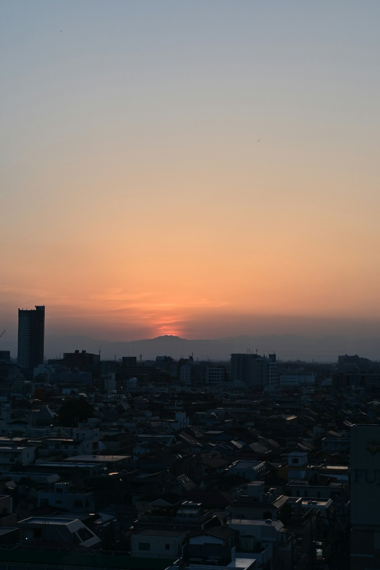 Stadtansicht bei Sonnenuntergang mit sichtbaren Gebäuden und Dächern